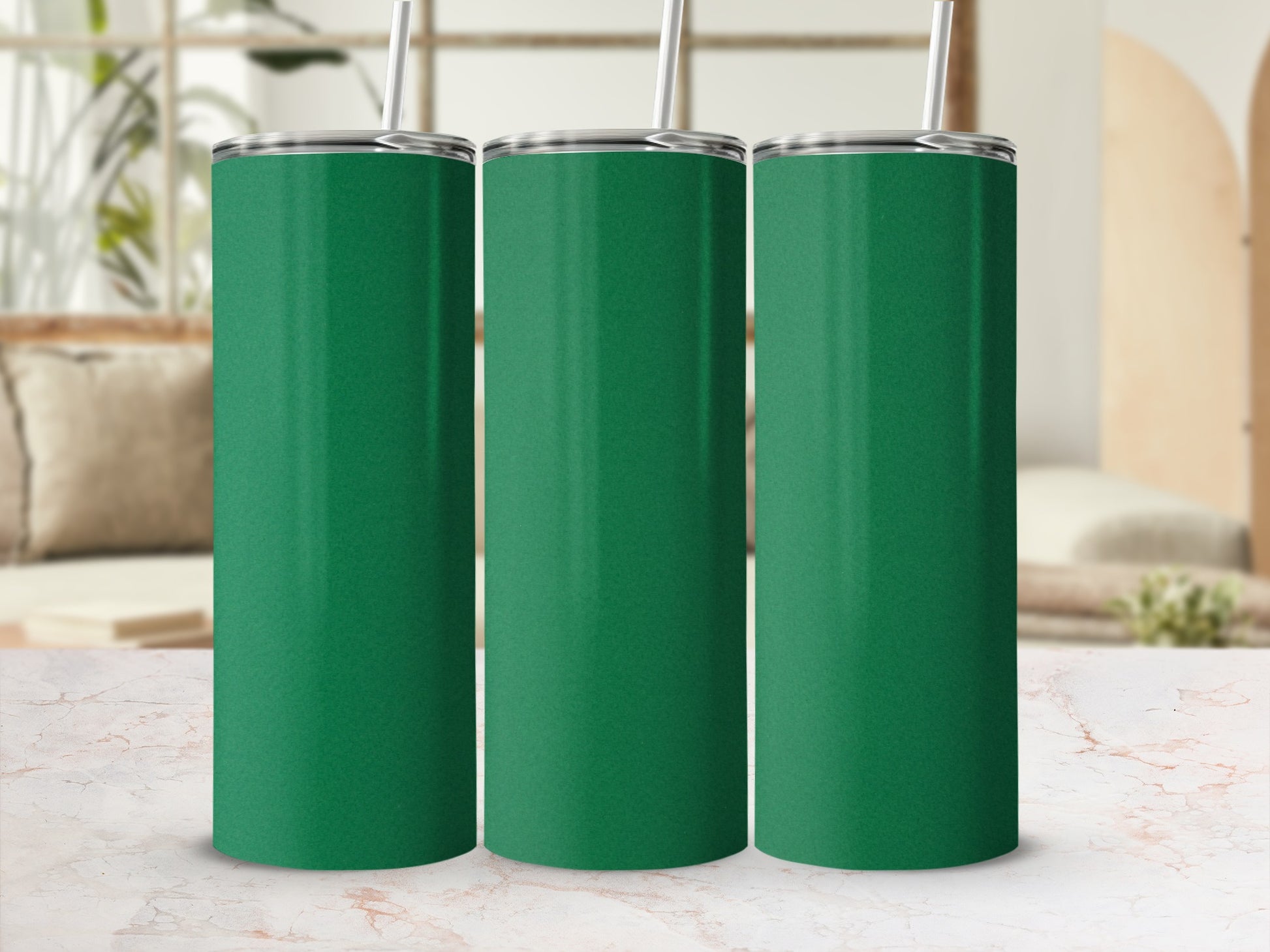 Three green tumblers with straws stand on a marble surface.