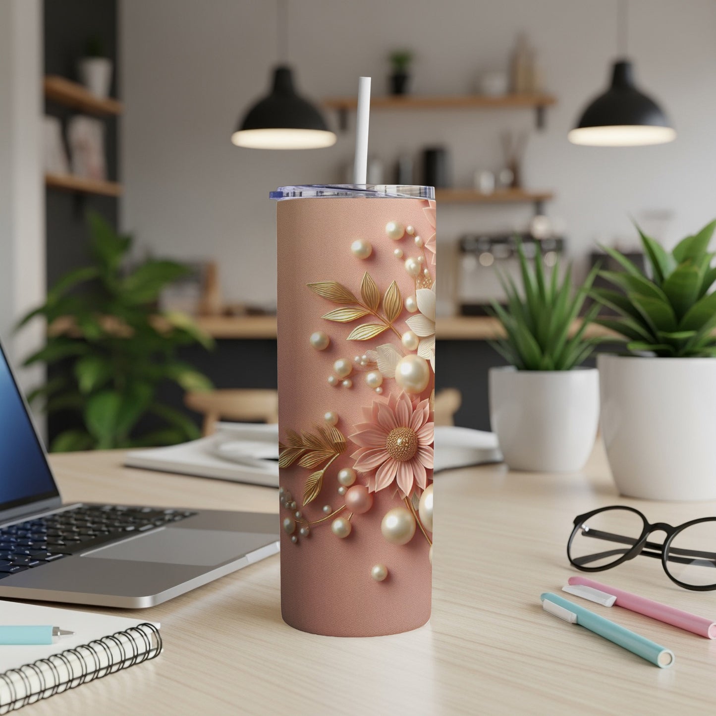 Pink tumbler with floral and pearl embellishments sits on a desk.