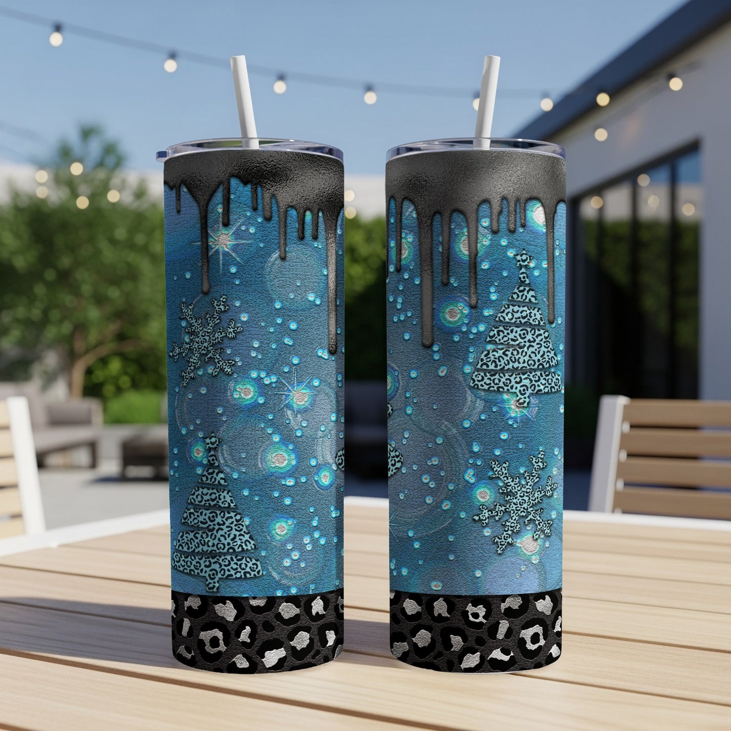 Two blue tumblers with dripping black tops, adorned with snowflakes and leopard print Christmas trees.