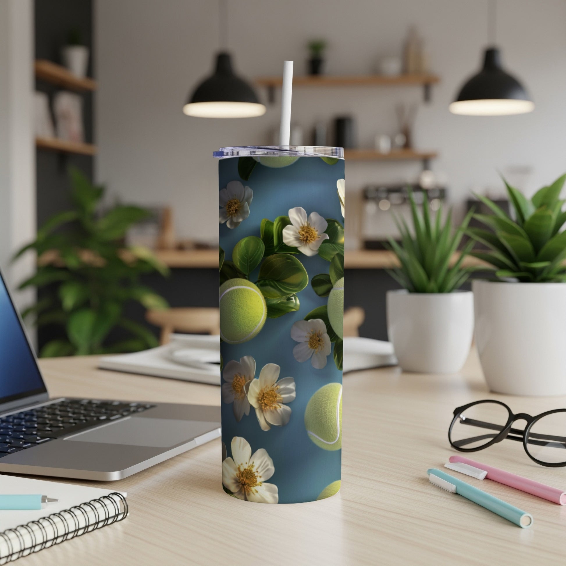 Tumbler with tennis balls and white flowers on a teal background.