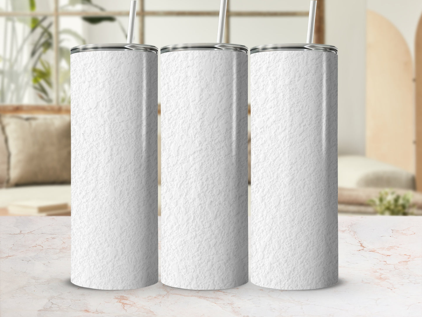 Three white textured tumblers with straws on a marble surface.
