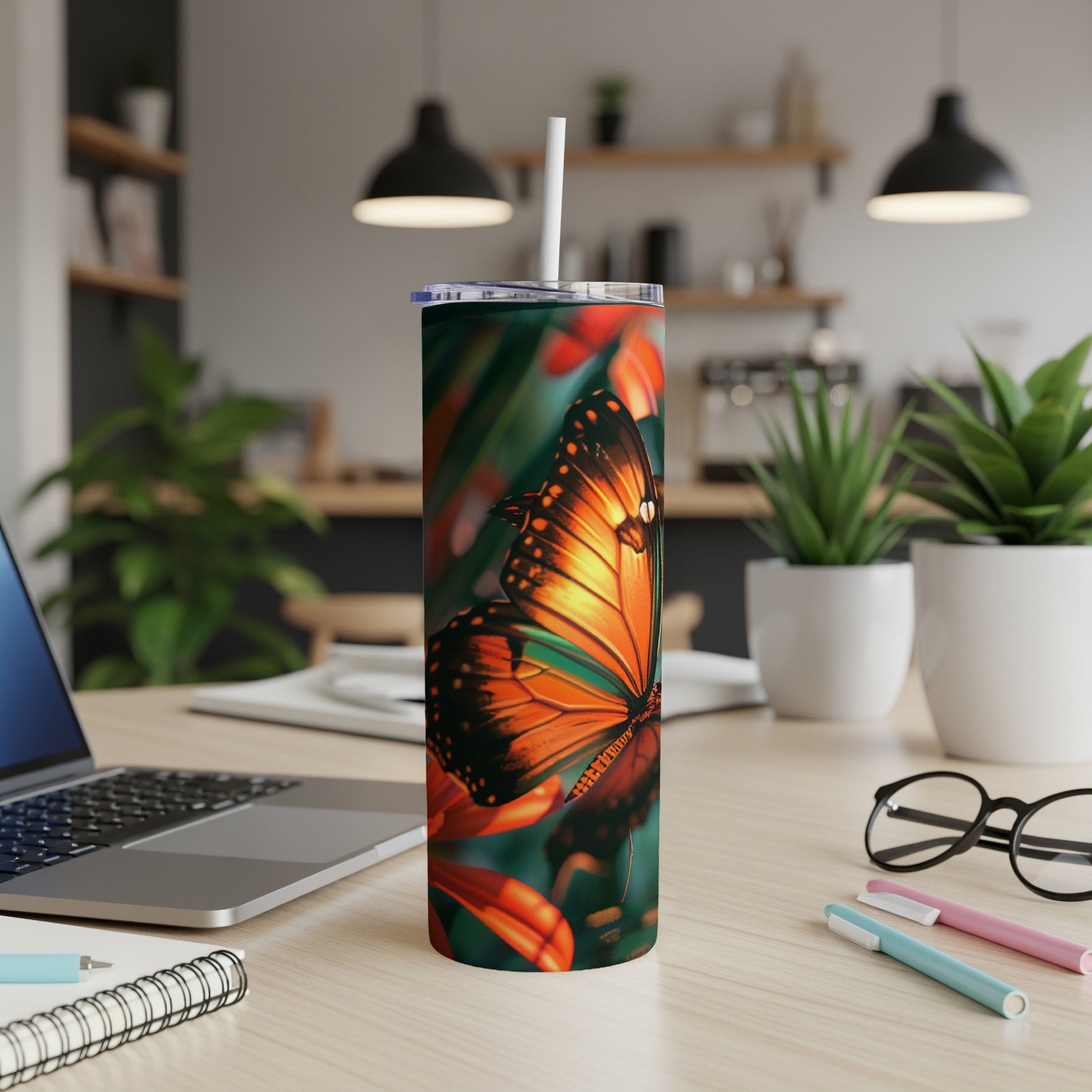 Orange monarch butterfly on a floral pattern tumbler with straw, on a desk.