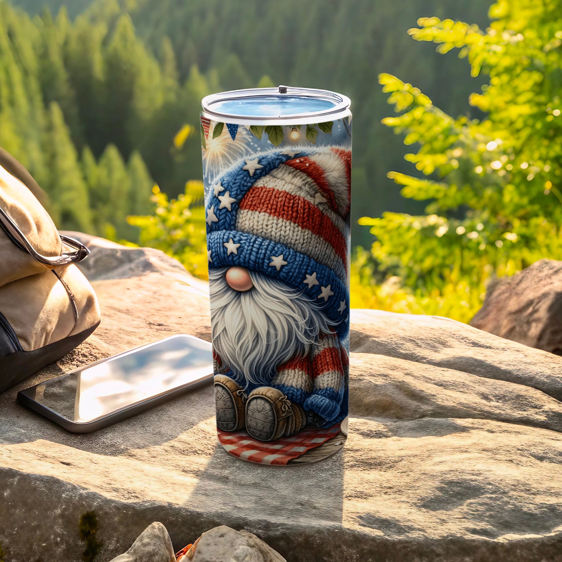 Patriotic gnome wearing striped hat sits on picnic blanket with phone and backpack.
