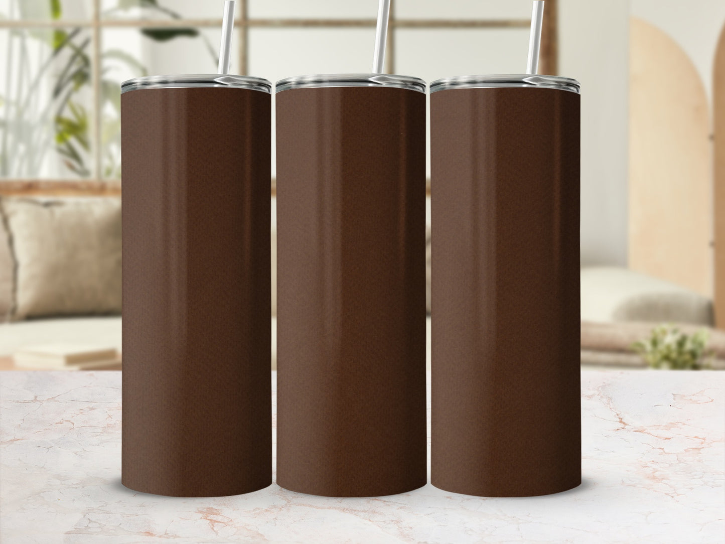 Three brown stainless steel tumblers with straws stand side-by-side.