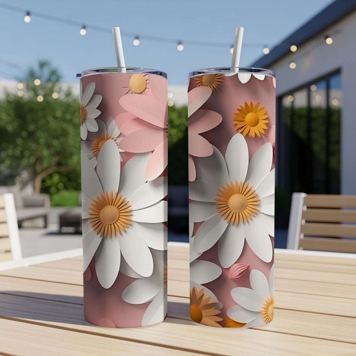 Two pink tumblers with white daisy floral design on a table.