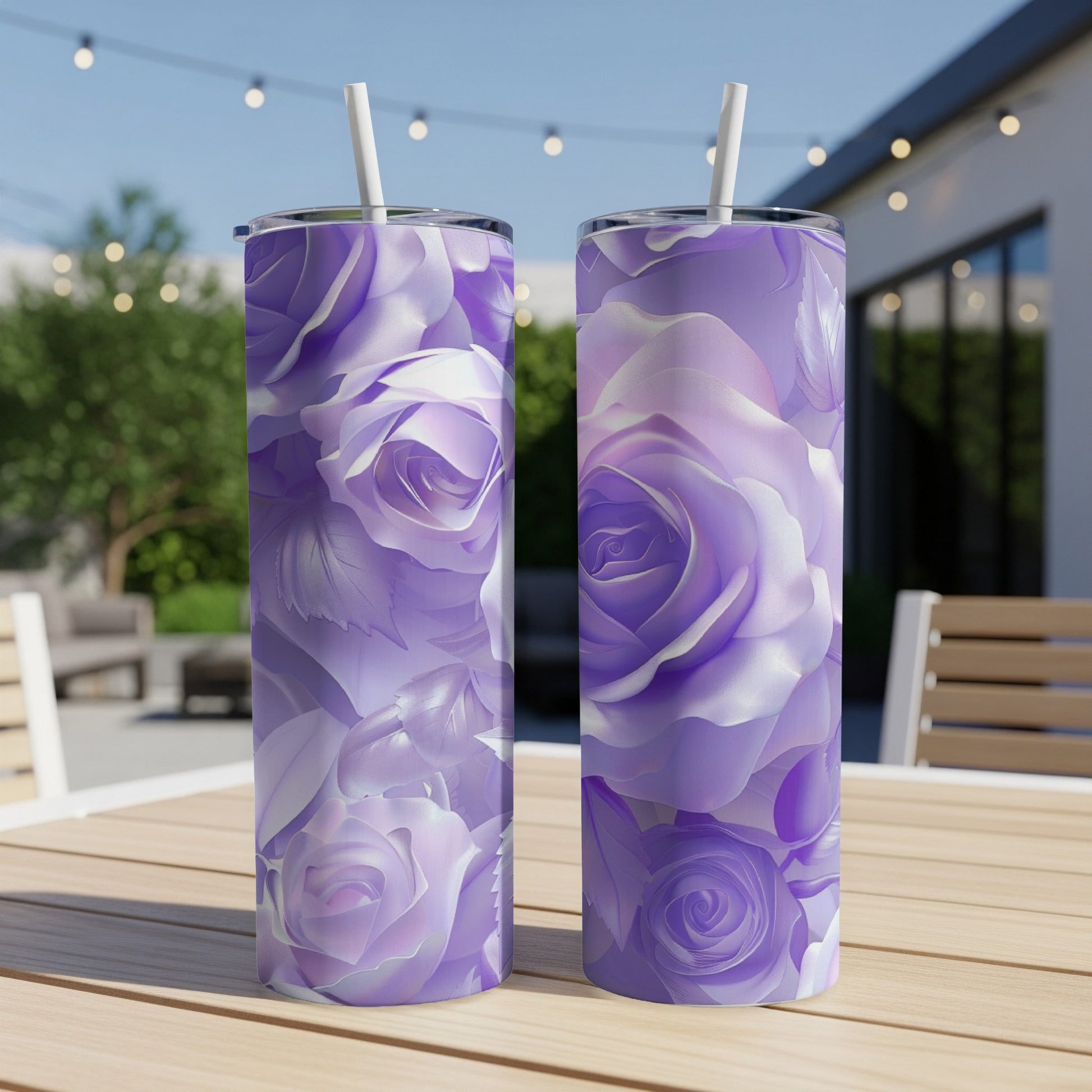 Two purple rose patterned tumblers with straws on a wooden table.