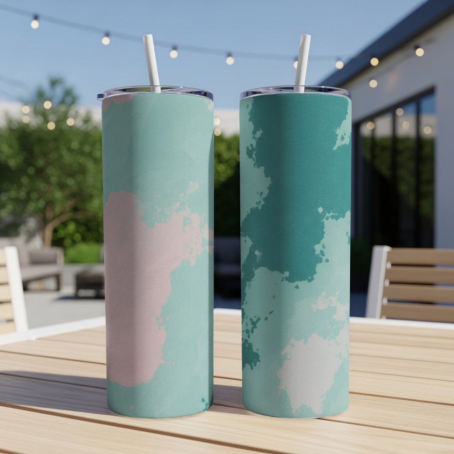 Two tumblers with abstract pink and teal watercolor patterns on a wooden table.