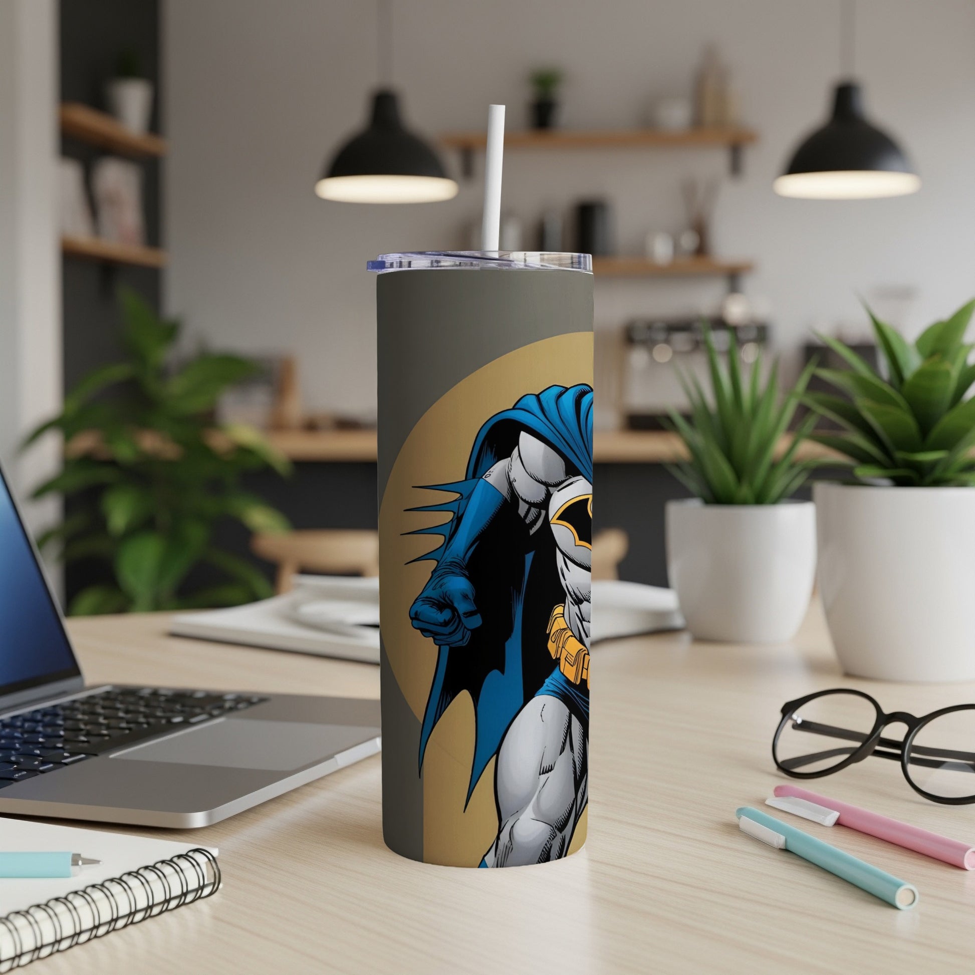 Batman illustration on a gray tumbler with a straw, on a desk.