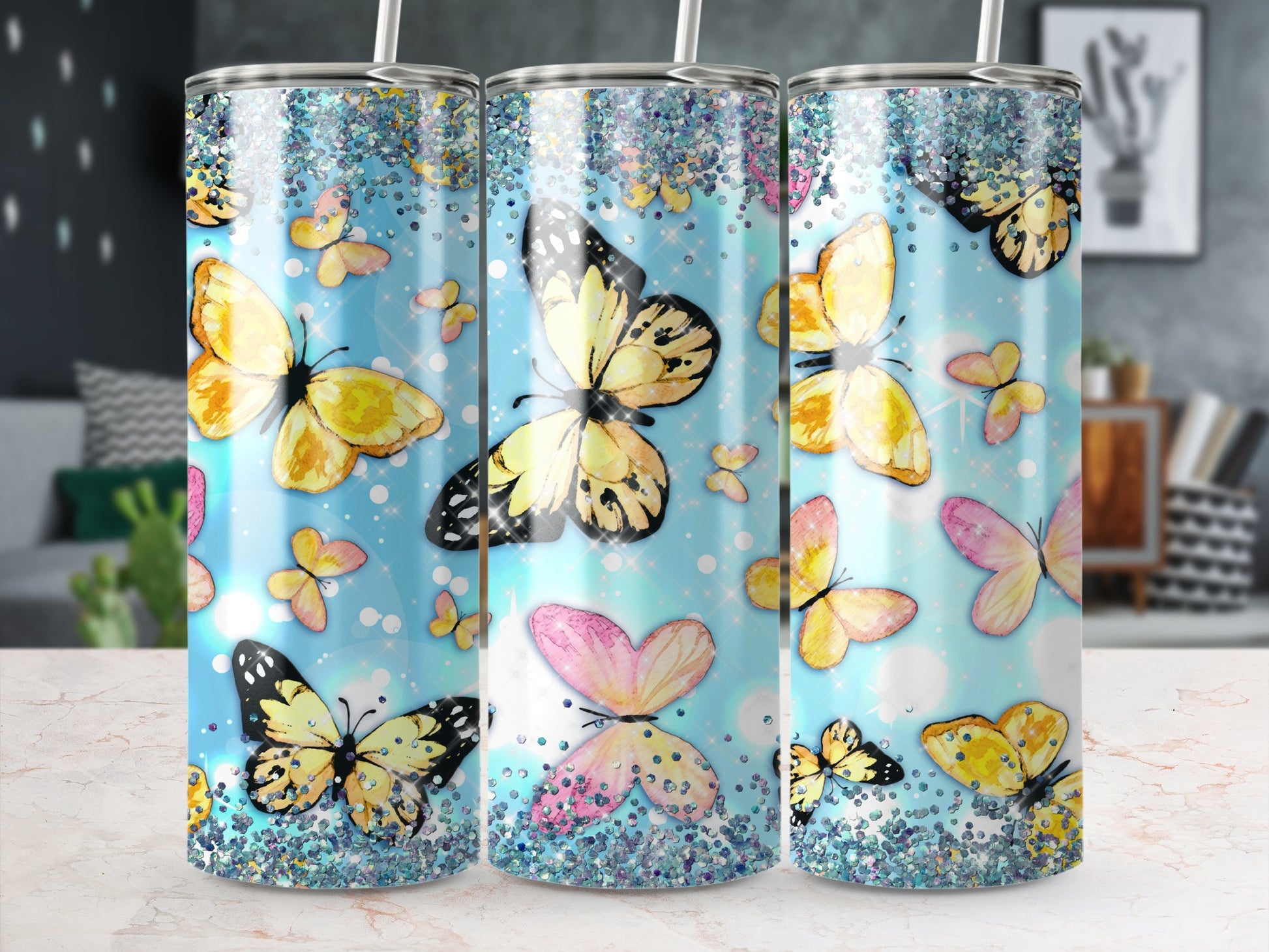 Three tumblers with colorful butterflies and glitter patterns.