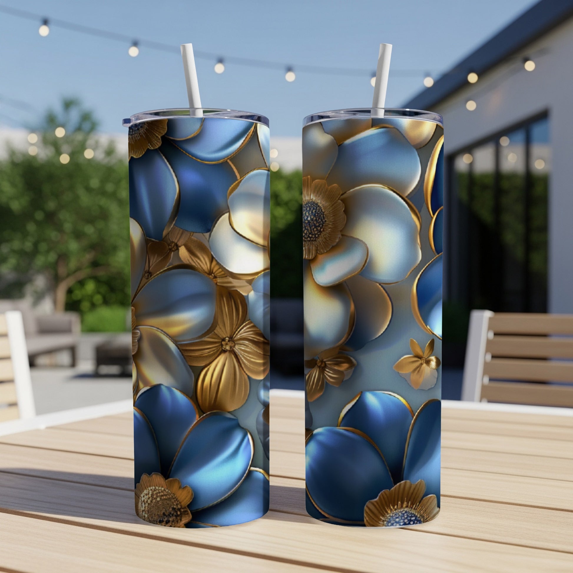 Two blue and gold floral patterned tumblers with straws on a wooden table.