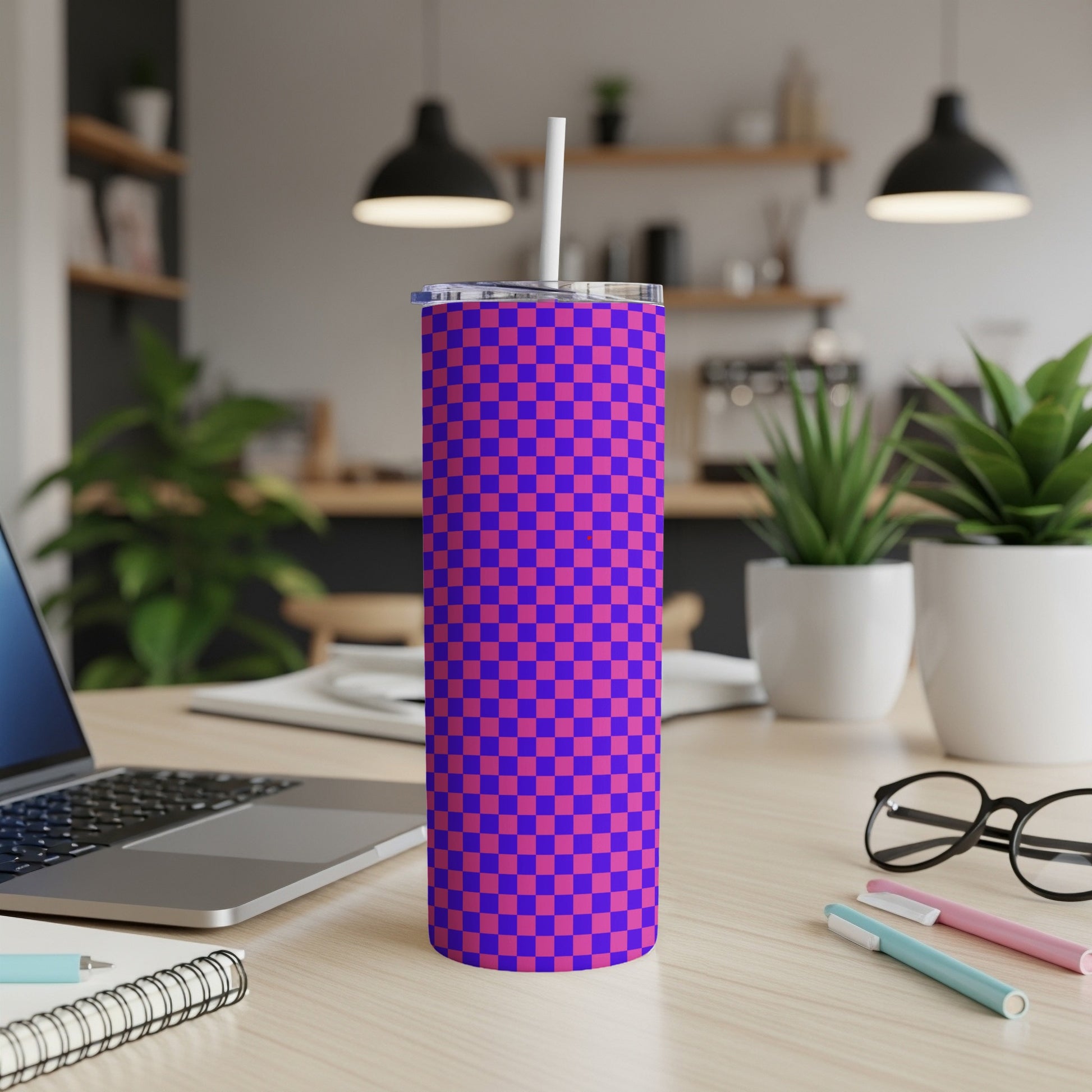 Blue and purple checkered tumbler with a straw on a desk.