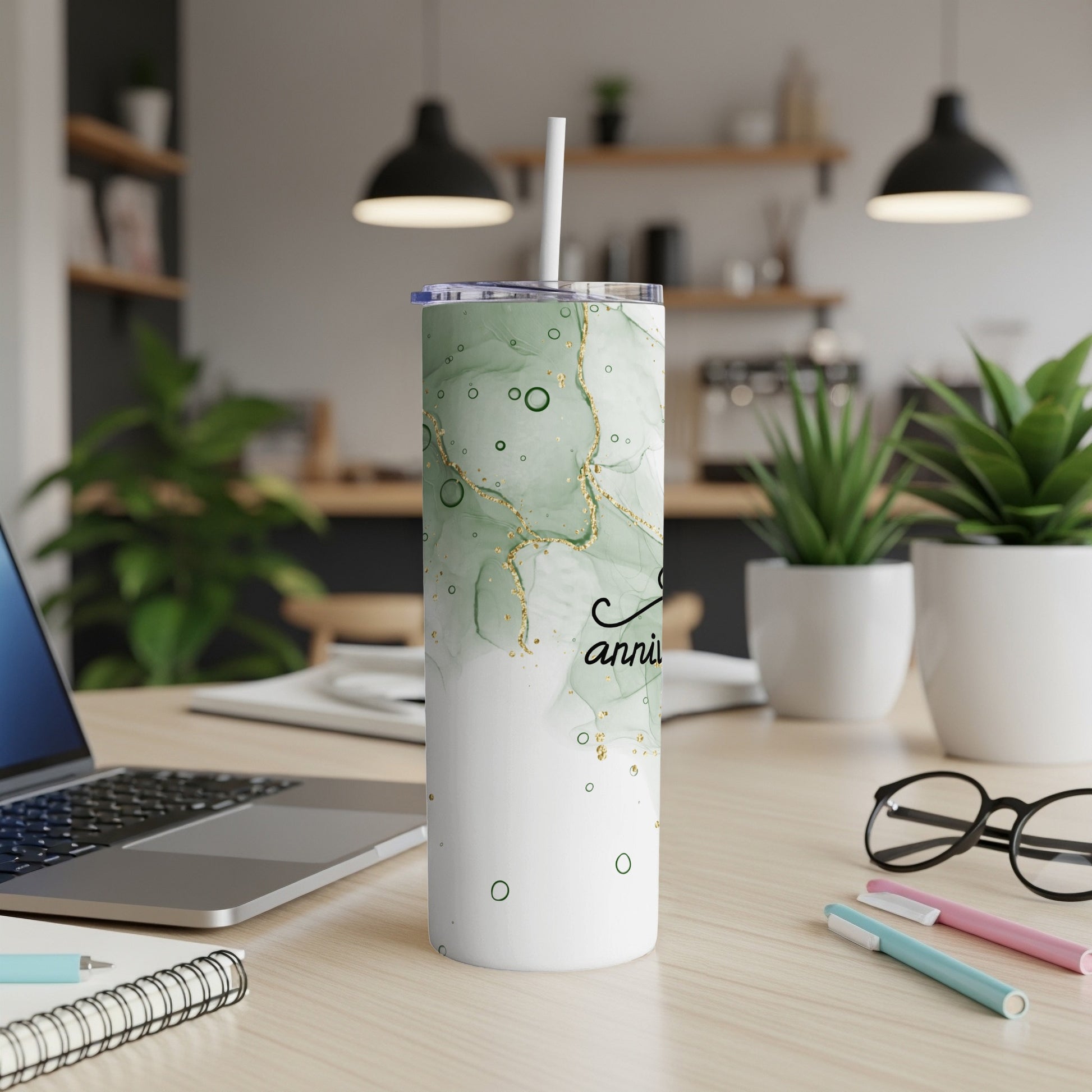 Green marbled tumbler with "anniversary" text, on a desk.