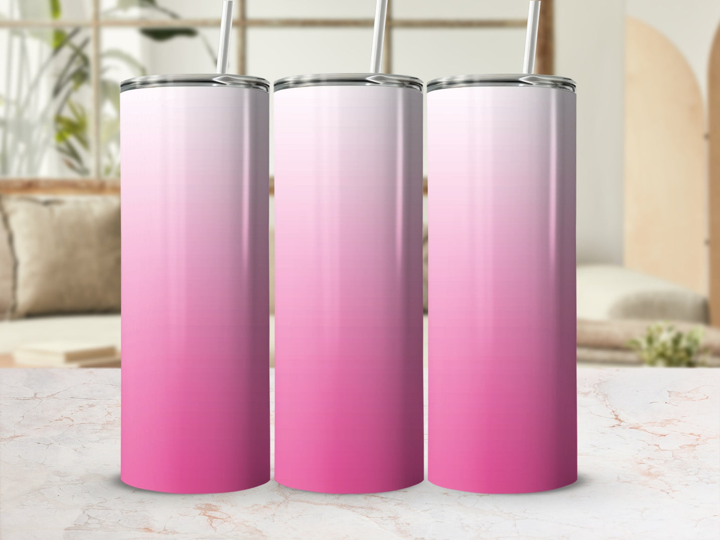 Three pink gradient tumblers with straws stand on a marble surface.