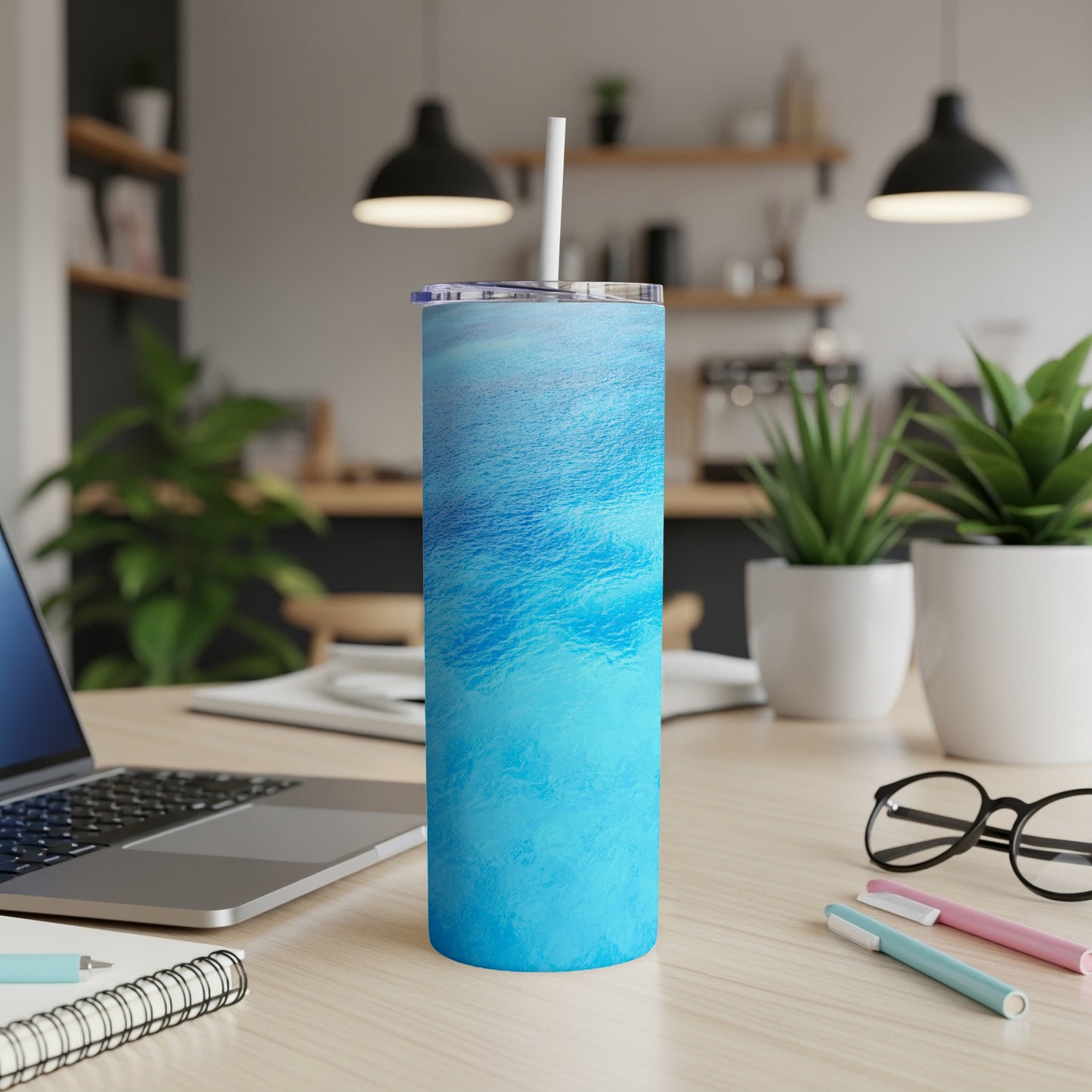 Blue ocean waves pattern on a 20oz tumbler with a straw on a desk.