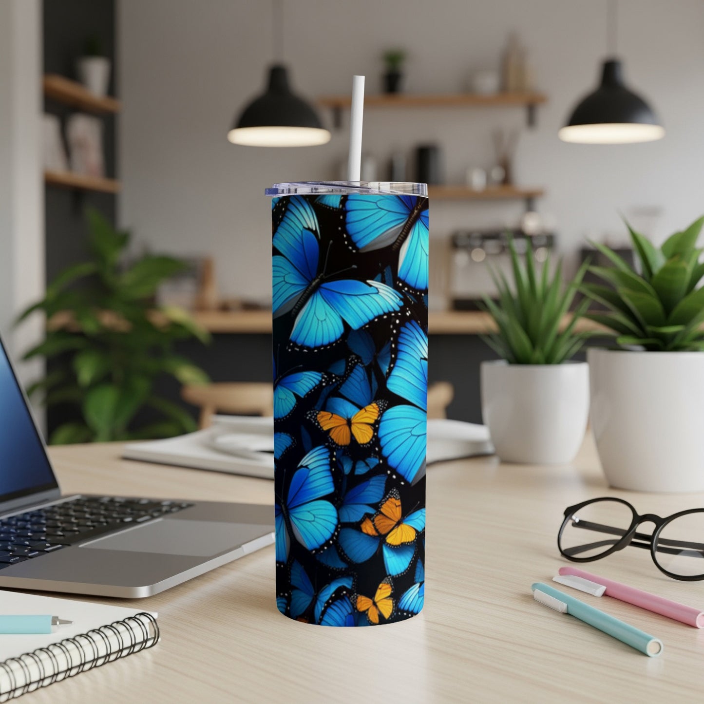 Blue and orange butterflies on a black background adorn a tall tumbler with a white straw.