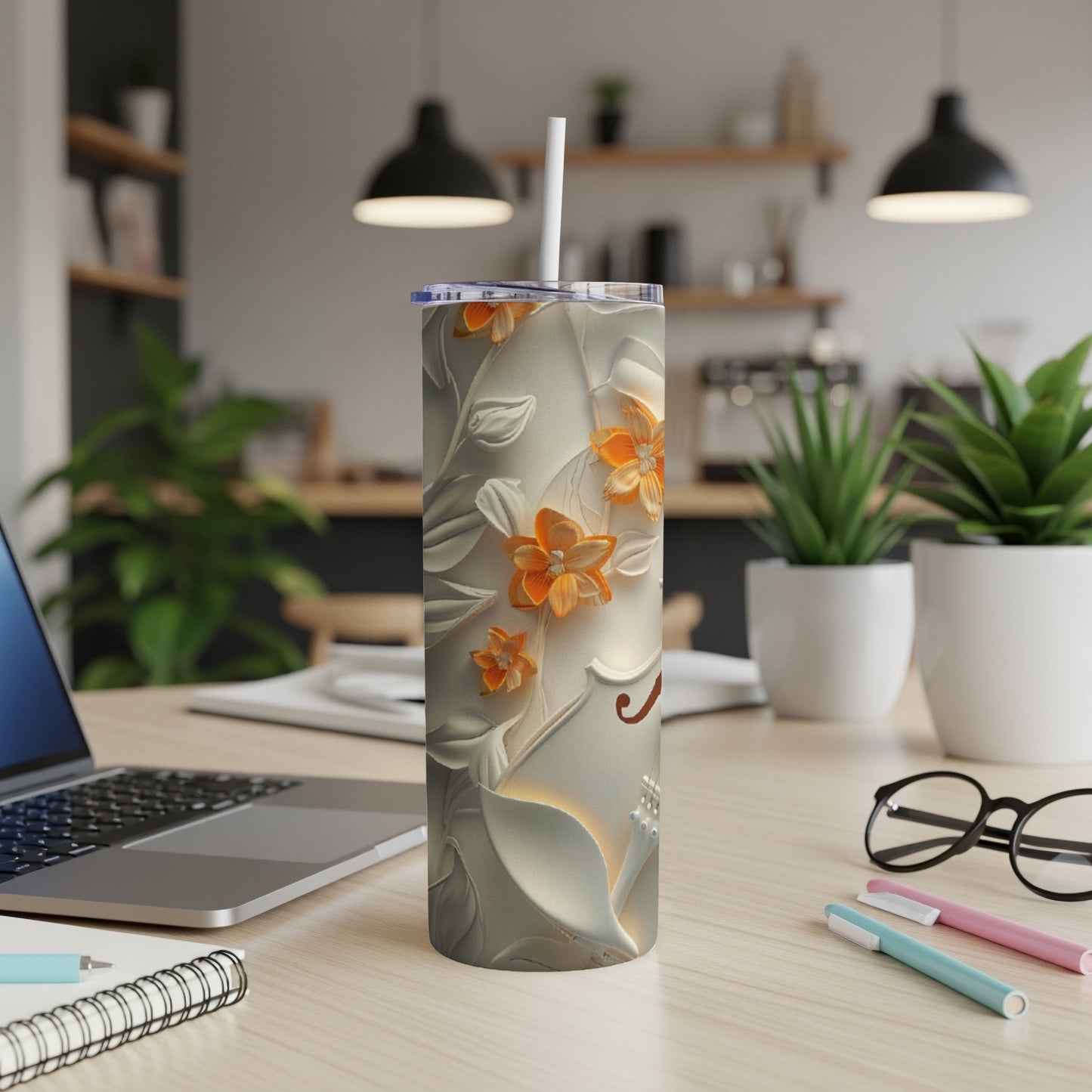 White tumbler with raised floral design and orange accents, resting on a desk.