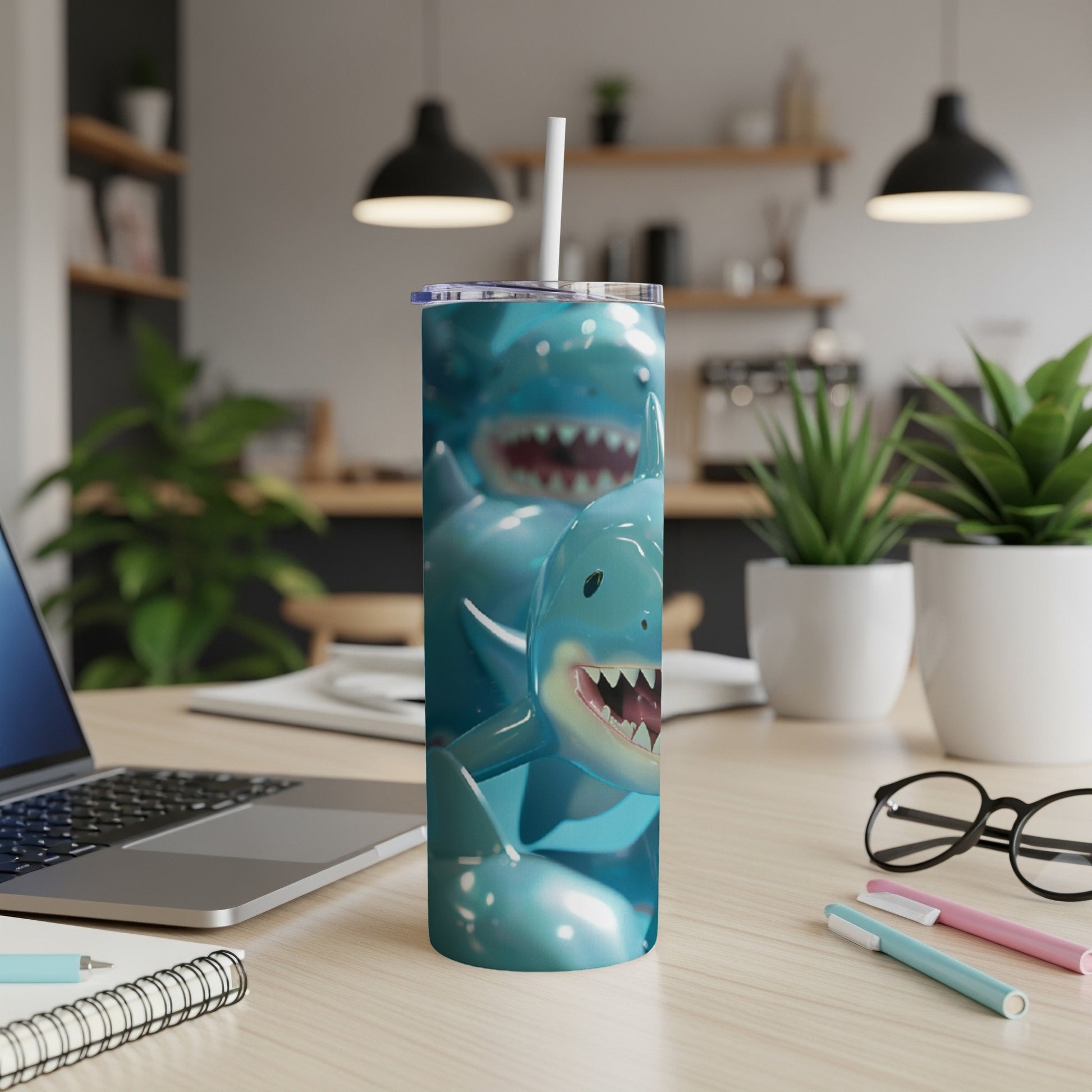 Blue tumbler with smiling shark cartoon characters and a straw.