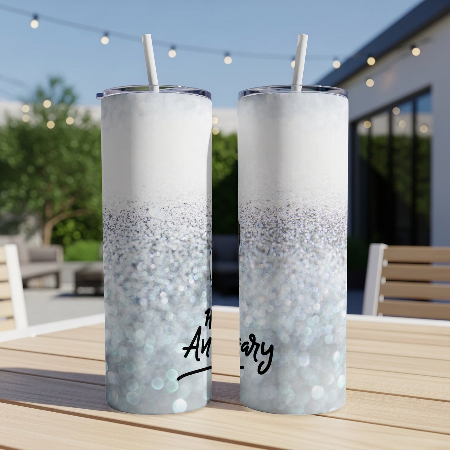 Glitter tumbler with "Happy Anniversary" text, white straw, outdoors.