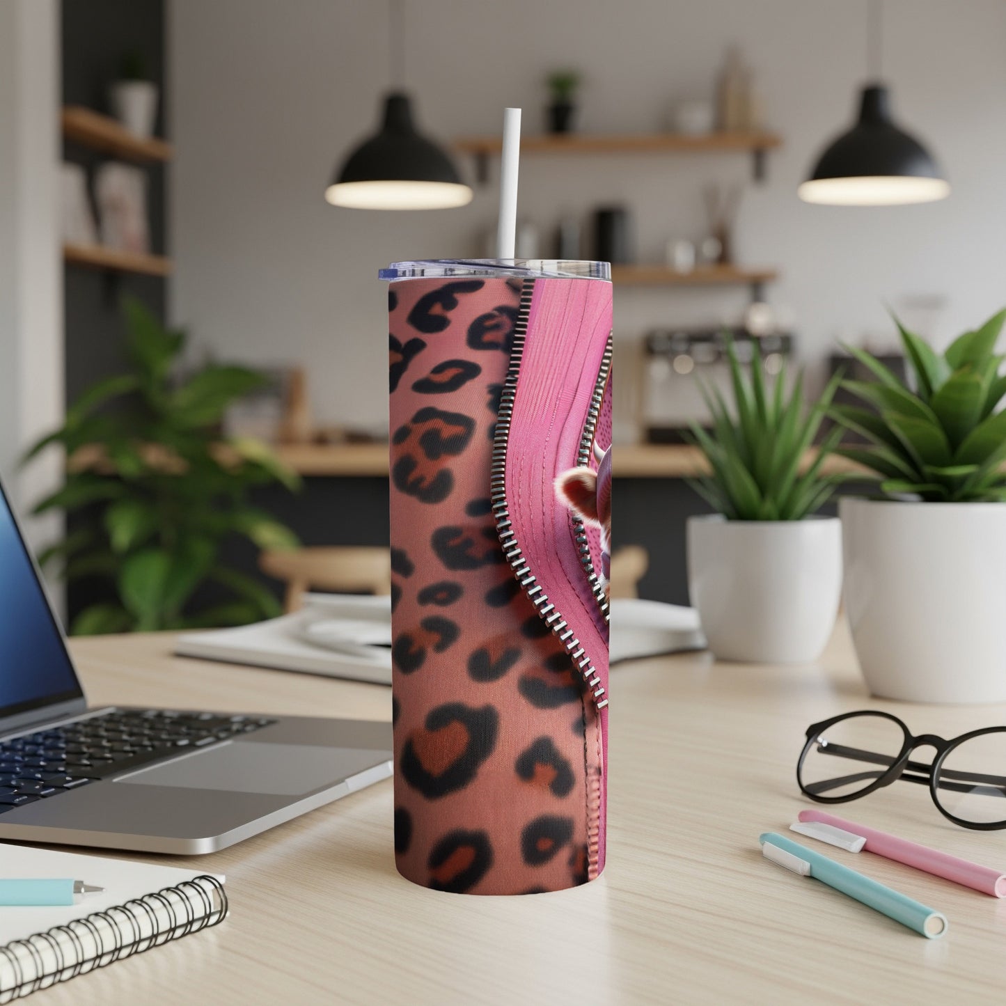 Pink leopard print tumbler with heart zipper detail on a desk.