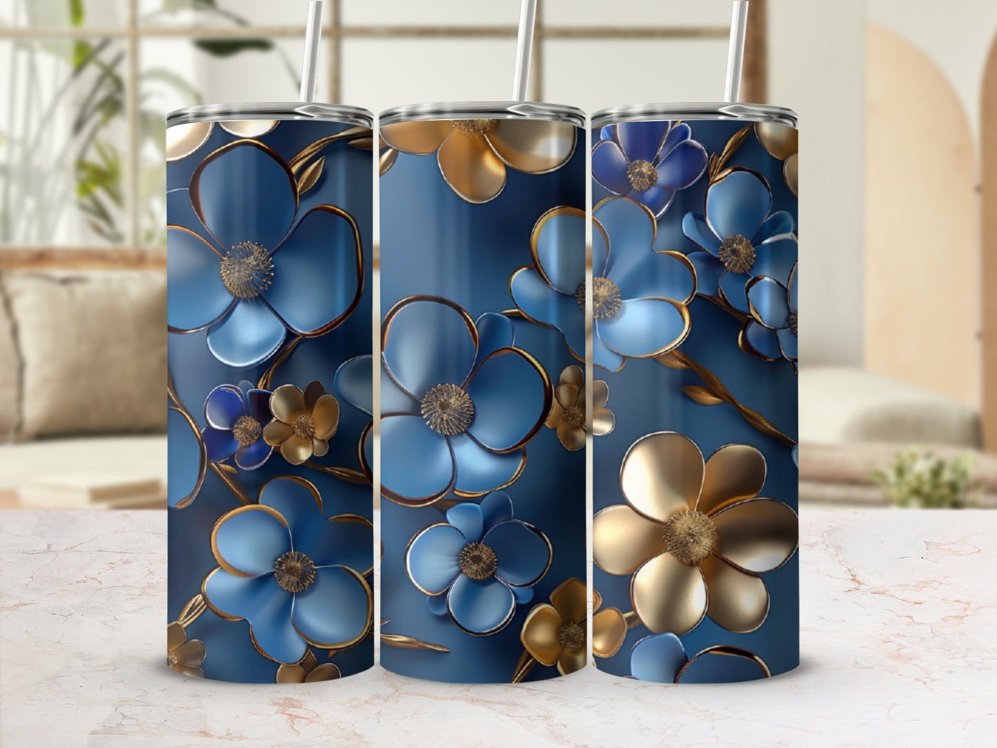 Three blue and gold floral tumblers with straws on a marble surface.