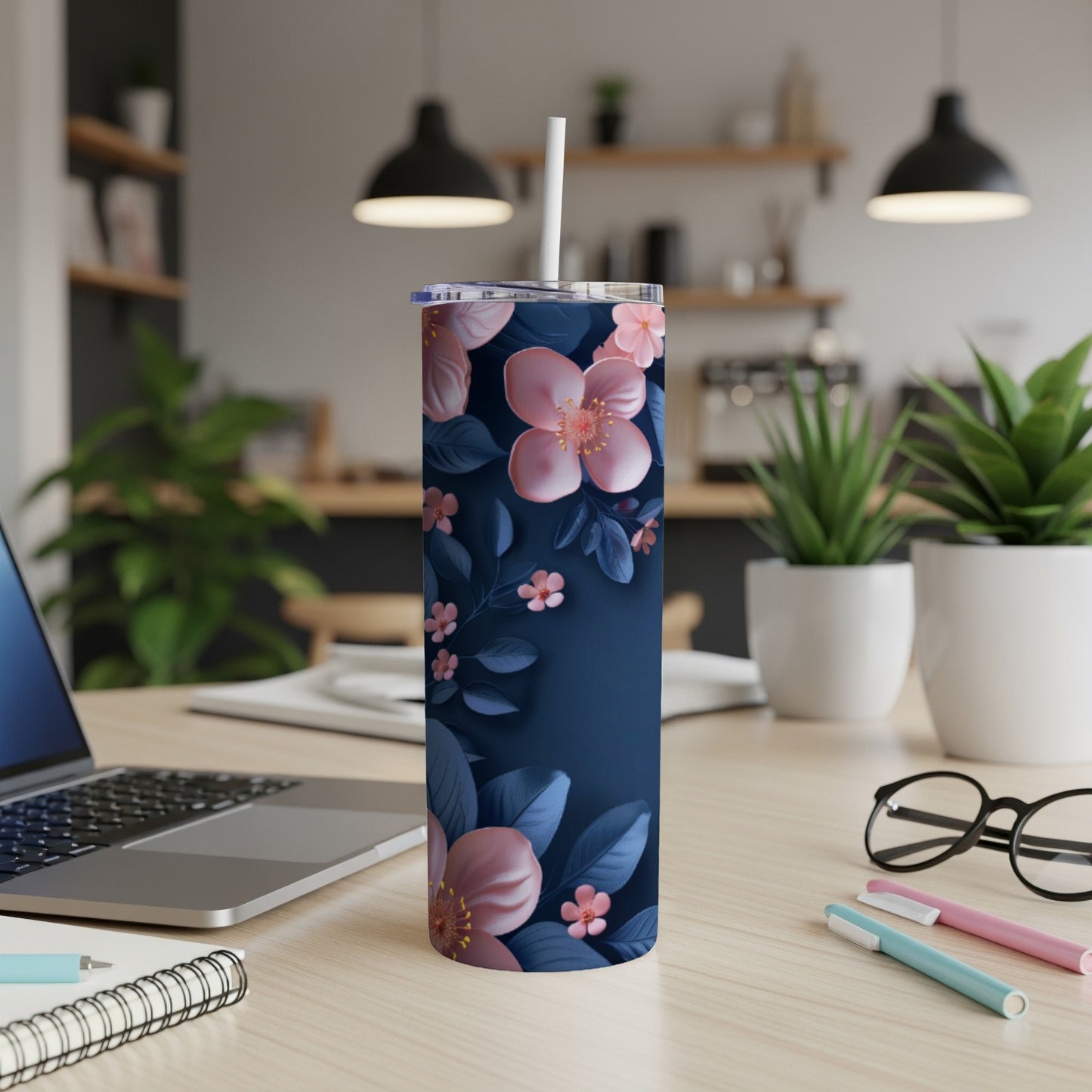 Dark blue tumbler with pink flowers and green leaves, on a desk.