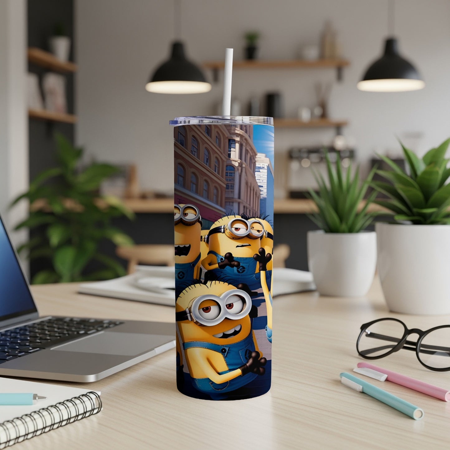 Minions on a blue tumbler with straw, on a desk.