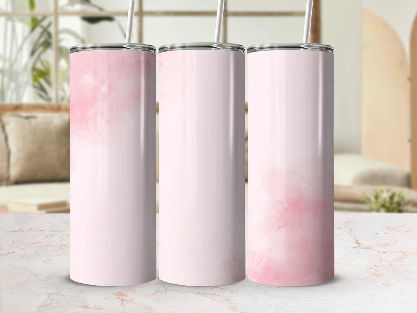 Three pink watercolor tumblers with straws on a marble surface.