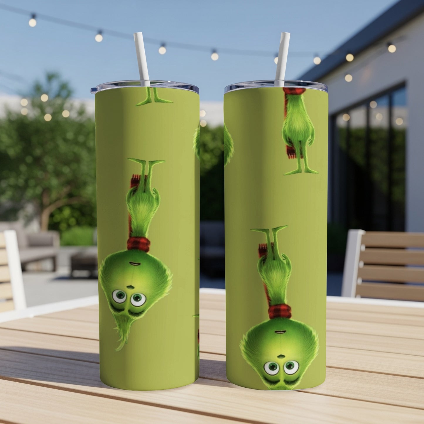 Two green tumblers with the Grinch character design, outdoors on a table.