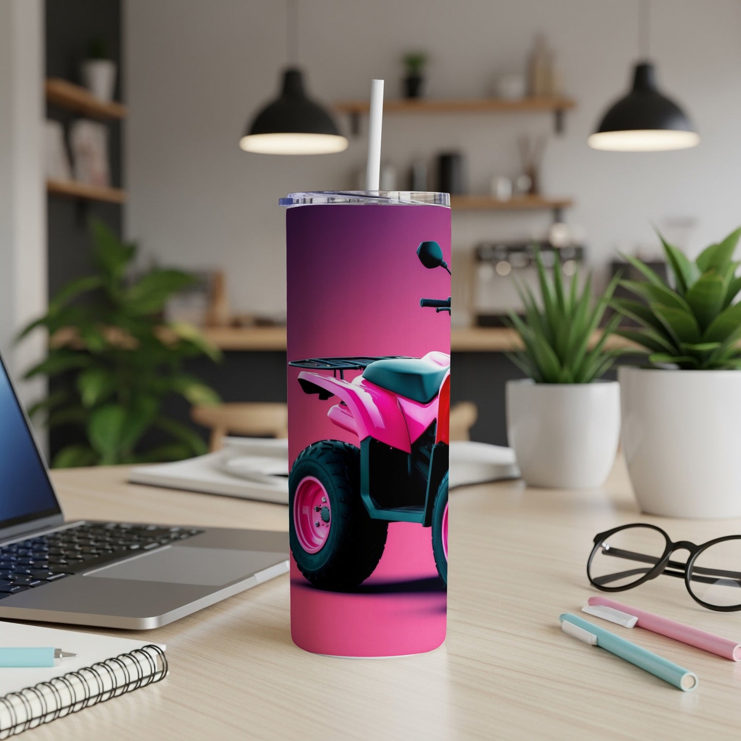 Pink ATV on a wooden desk with a laptop and plants.