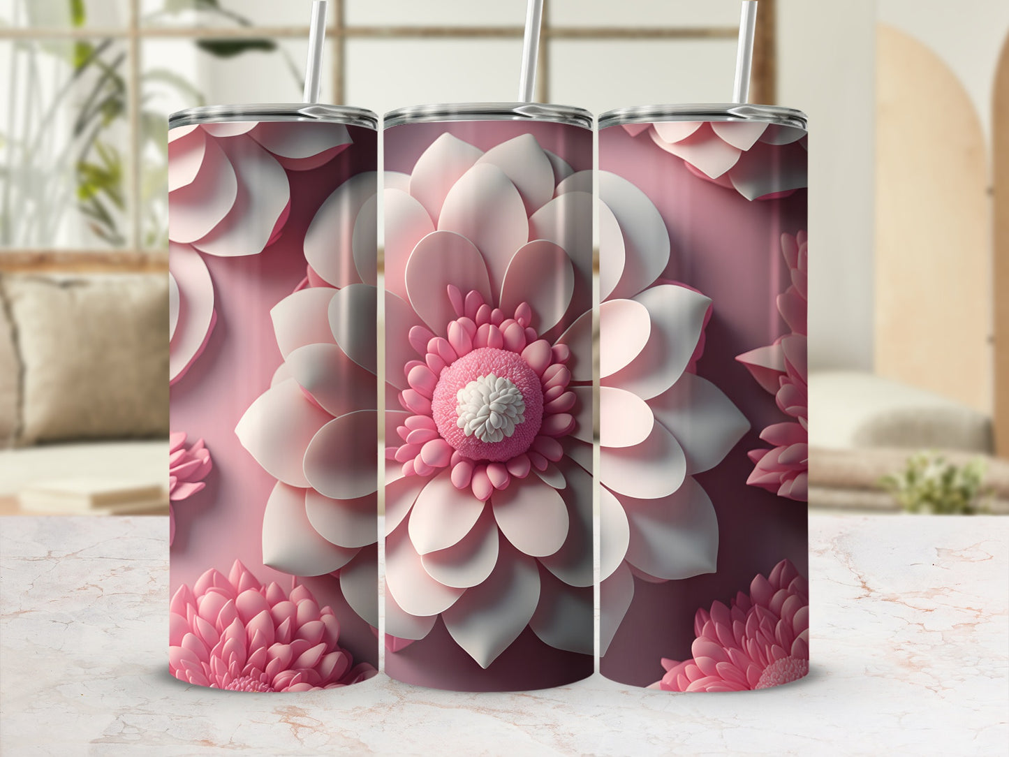 Three pink floral tumblers with straws on a marble surface.
