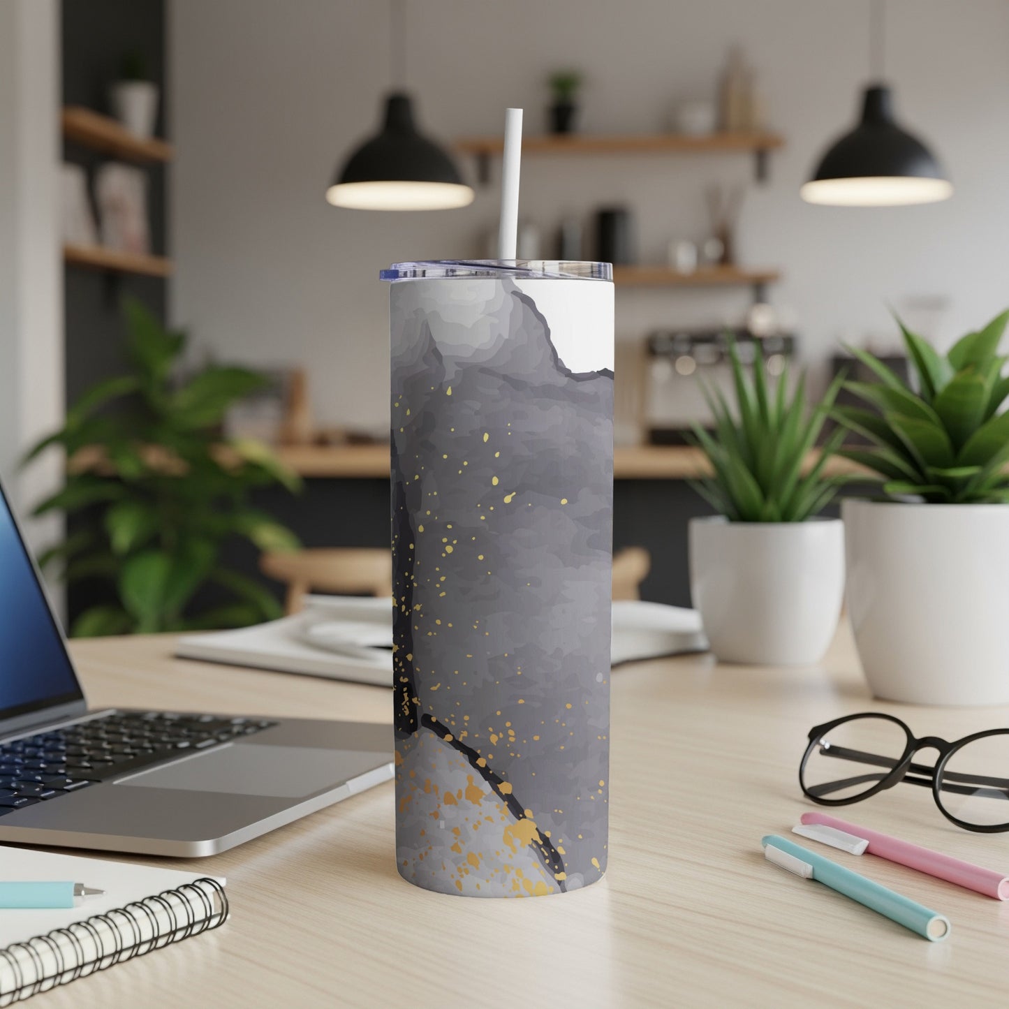 Gray and gold abstract watercolor tumbler with straw on desk.