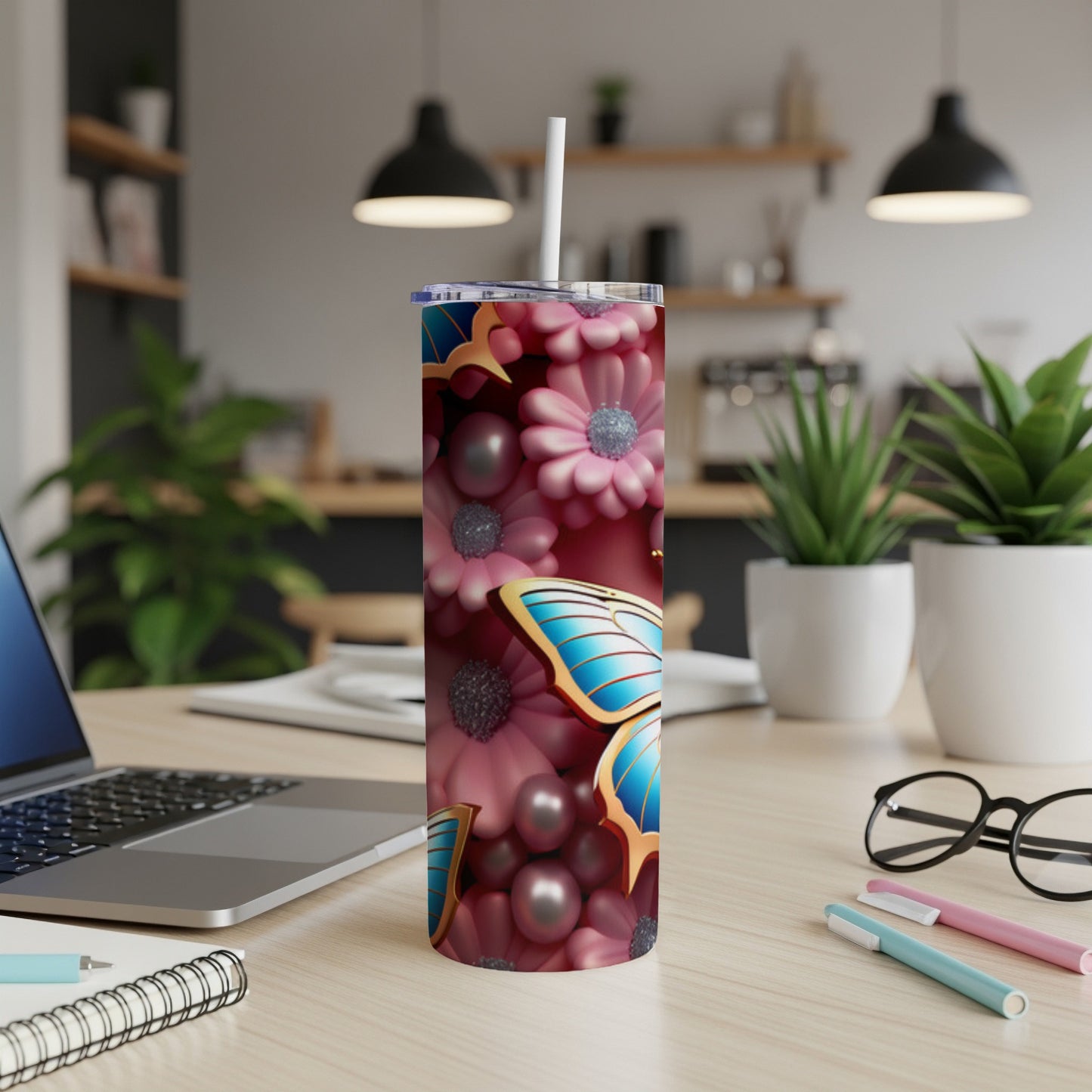 Pink floral pattern tumbler with blue butterfly, white straw, and office desk background.