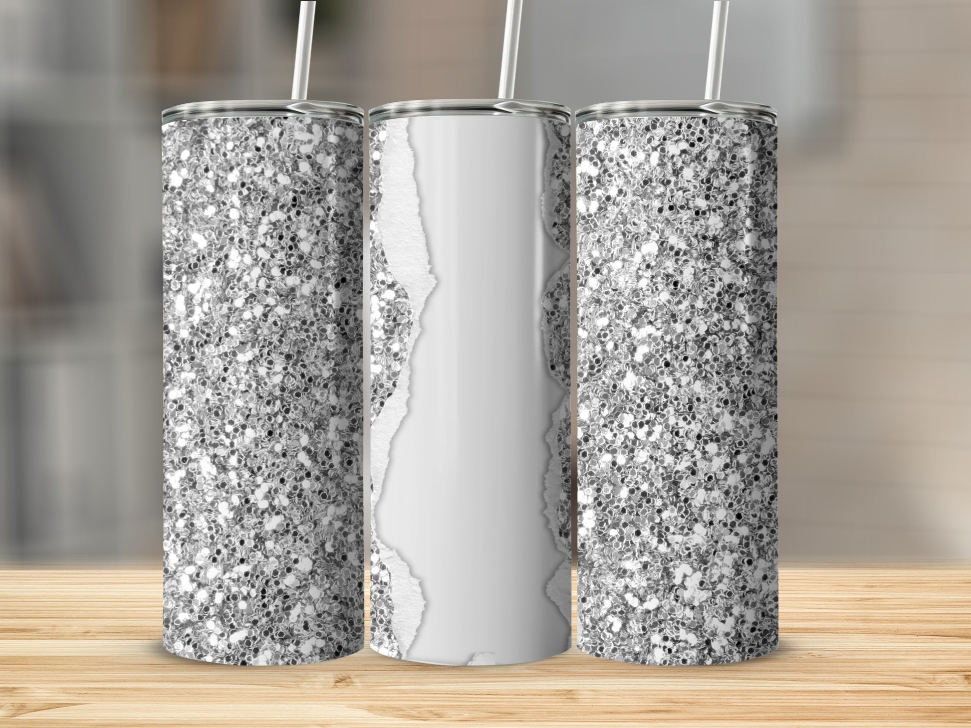 Three glitter-covered tumblers with white paper overlay on a wooden surface.