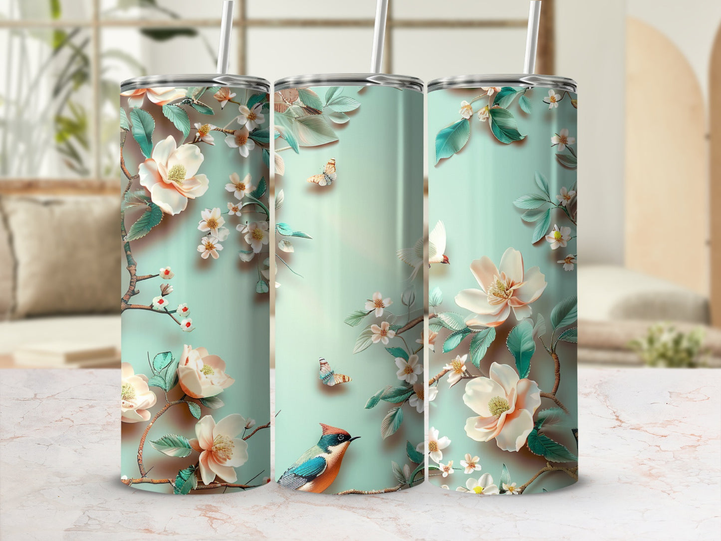 Three tumblers with a floral and bird design on a marble countertop.