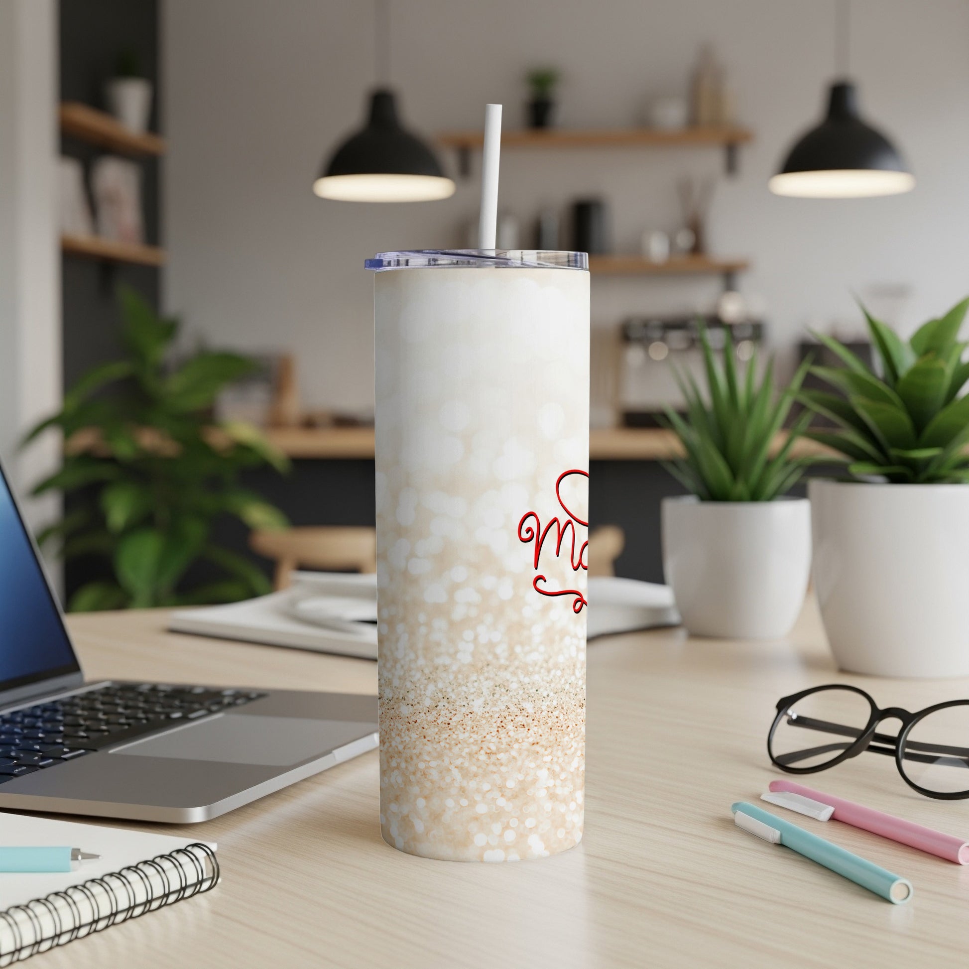 White speckled tumbler with "Merry" text and a straw on a desk.