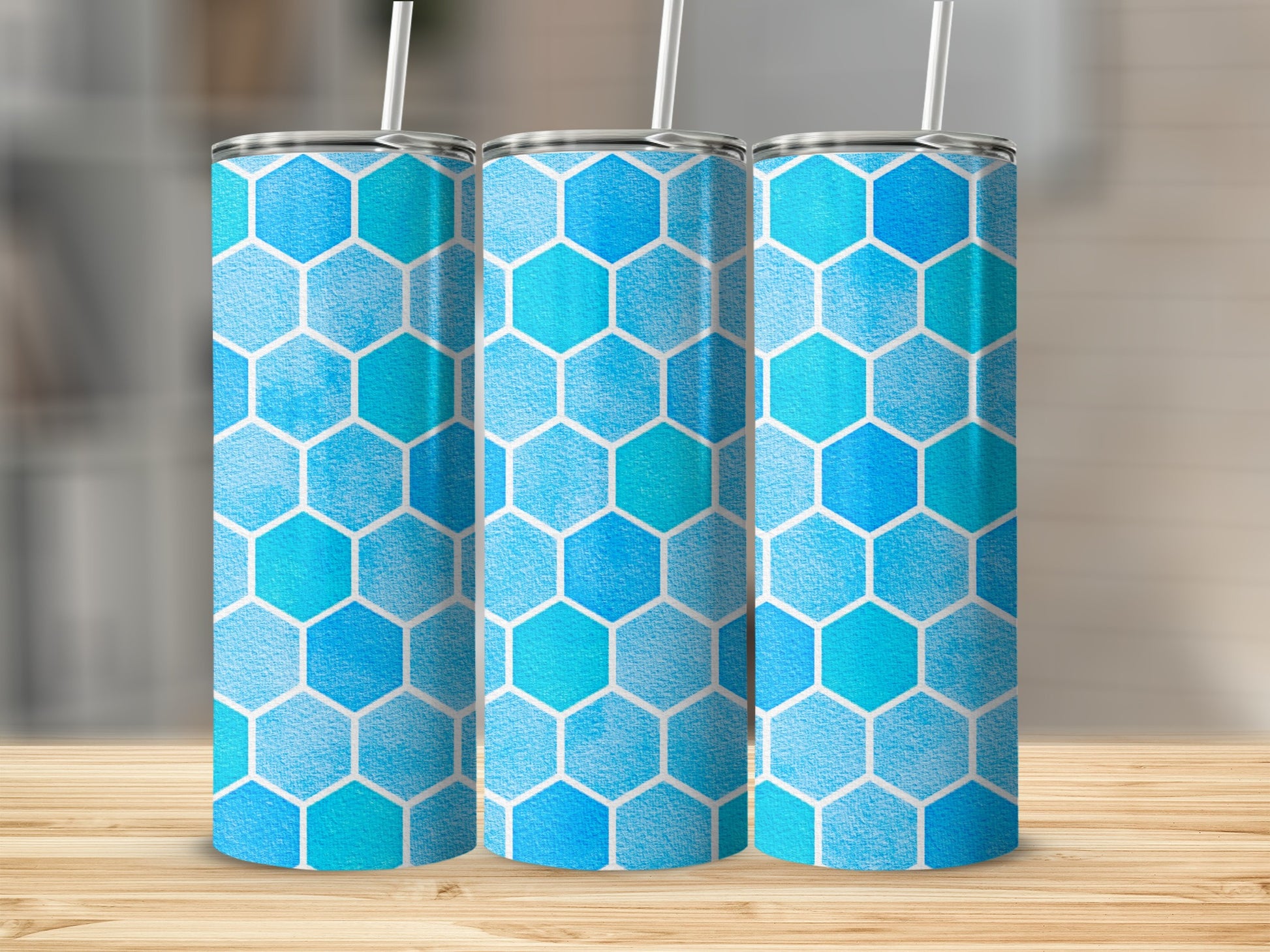 Three tumblers with a blue and turquoise hexagon pattern and white straws.