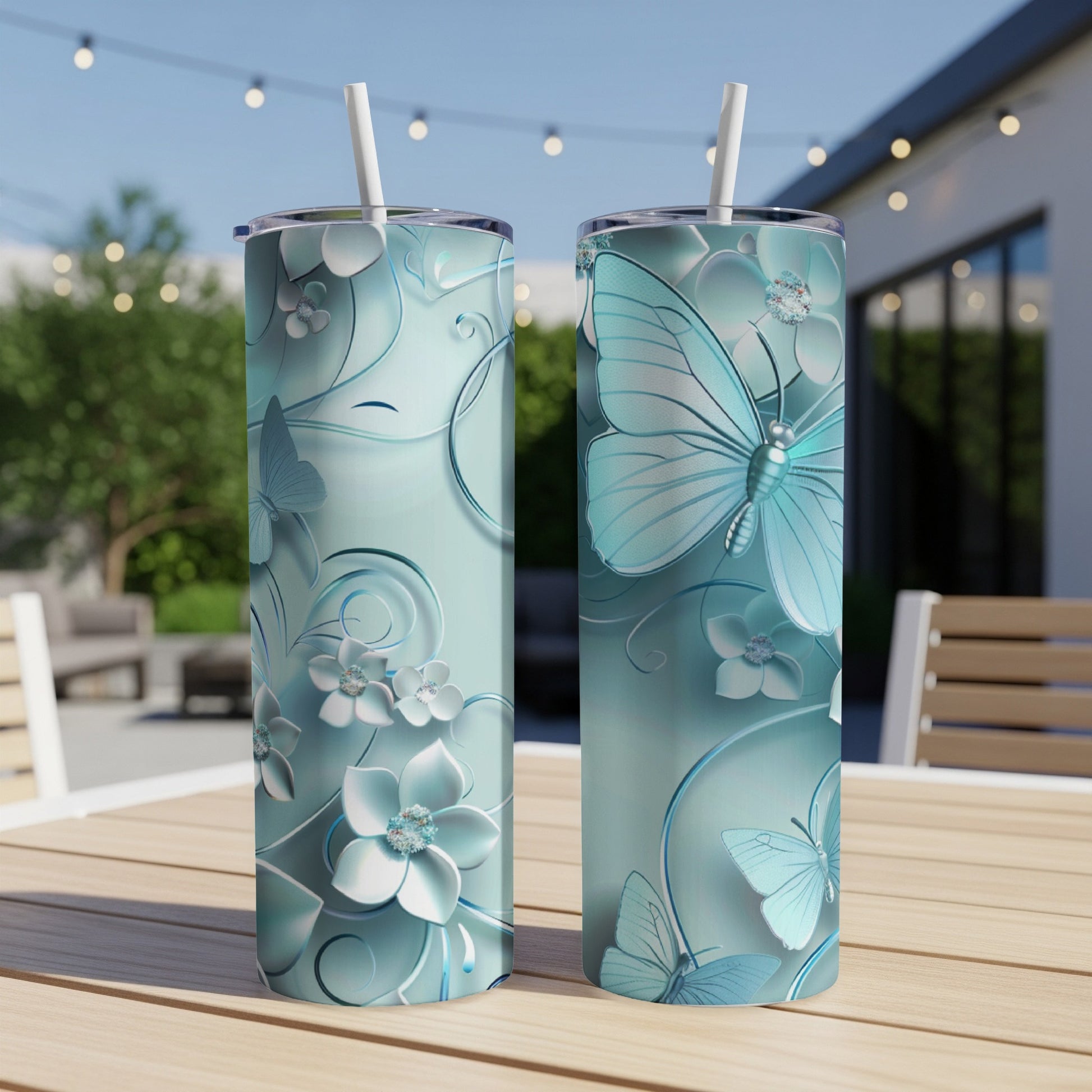 Two light blue tumblers with embossed butterfly and floral designs sit on a table.