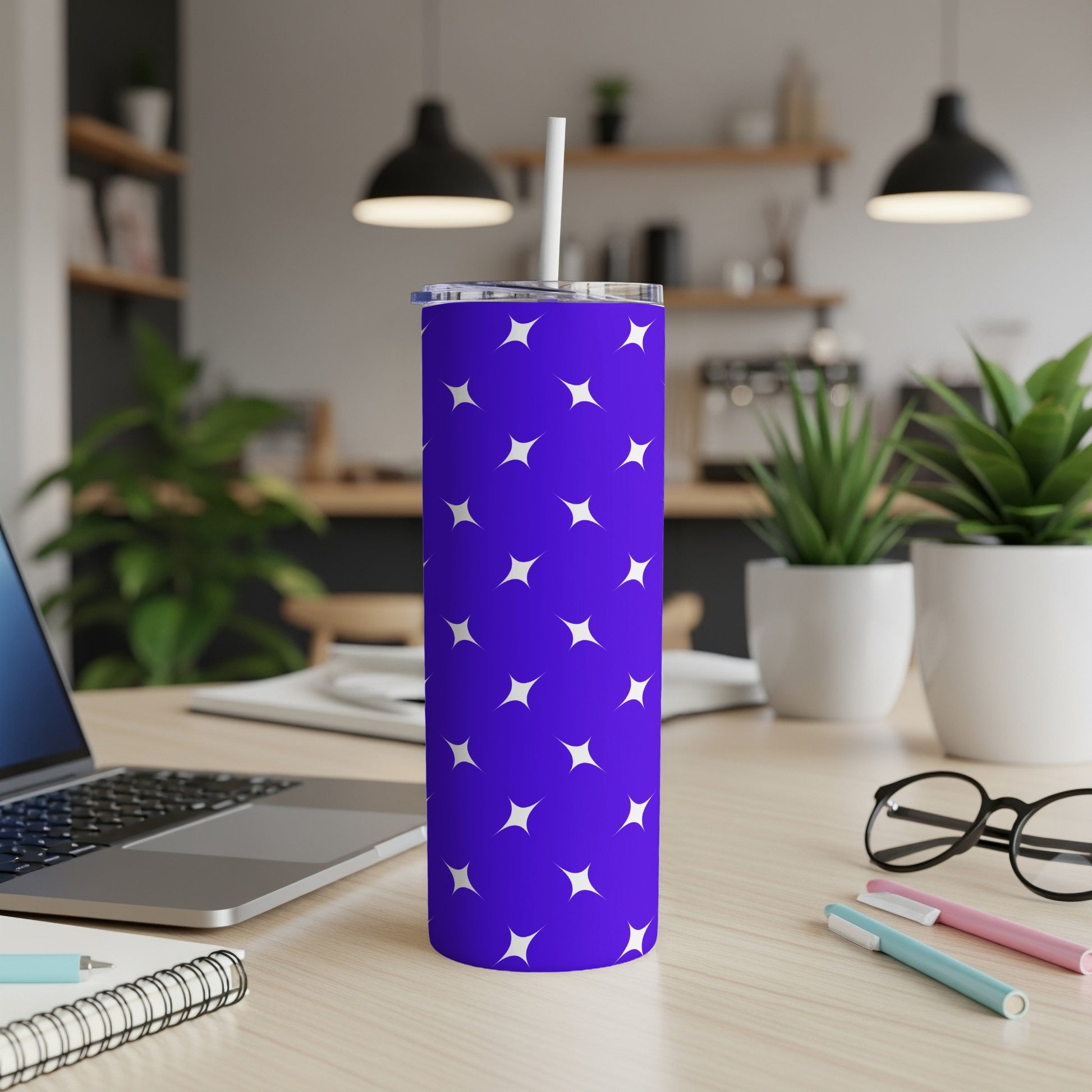Purple tumbler with white stars and a white straw on a wooden desk.