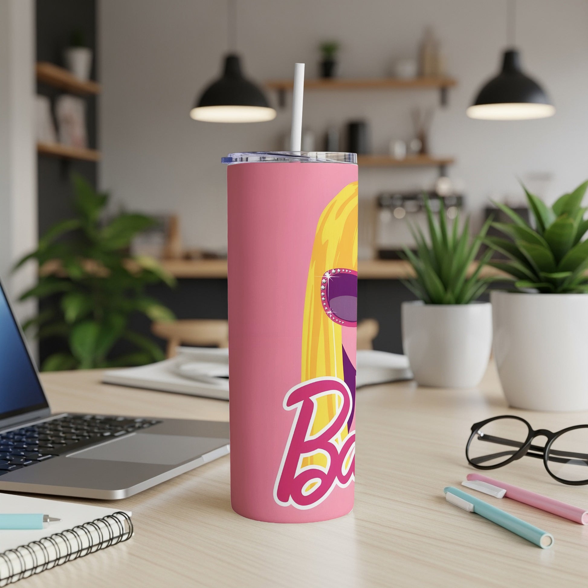 Pink Barbie tumbler with blonde hair and sunglasses on a desk.