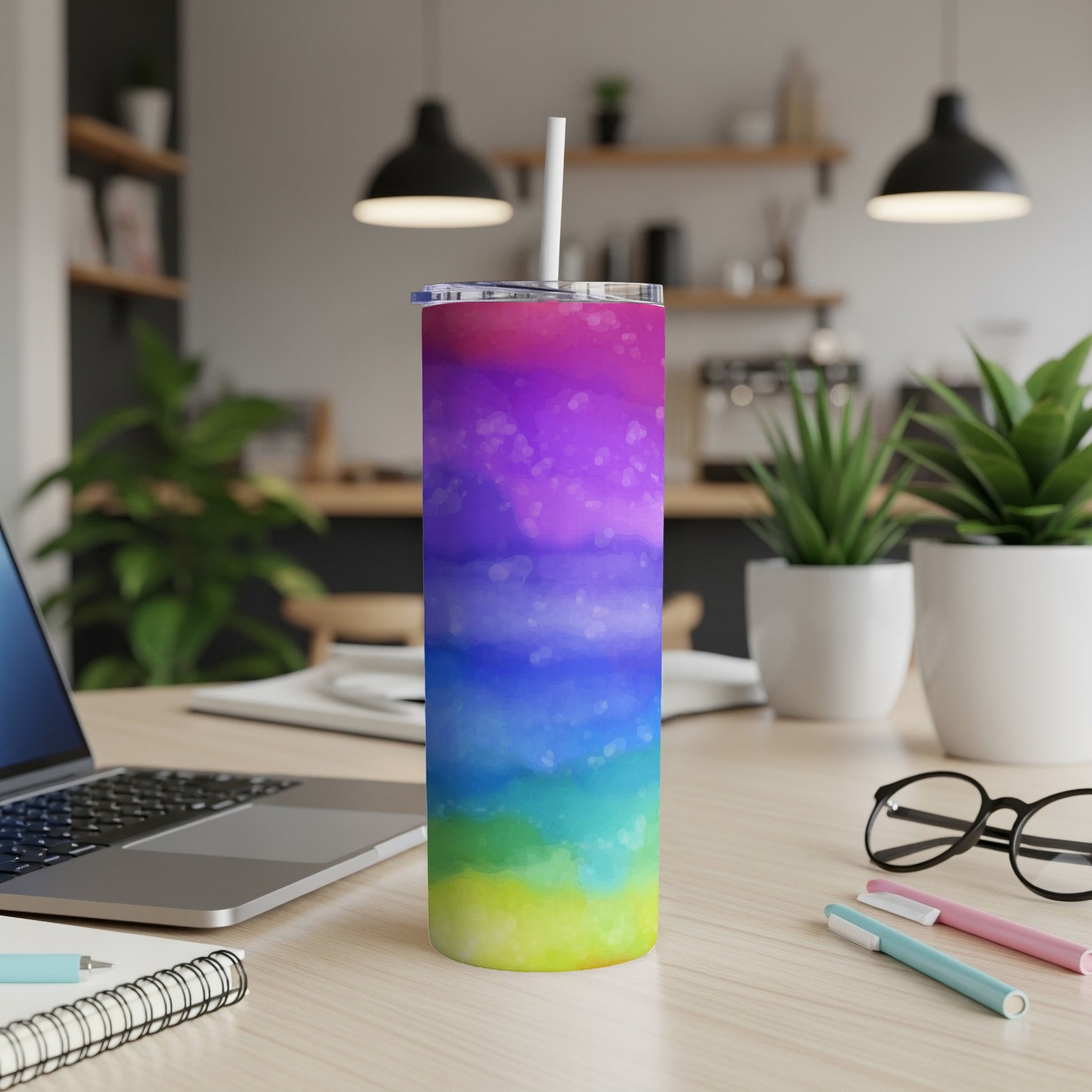 Rainbow watercolor tumbler with white straw on a desk with laptop and glasses.