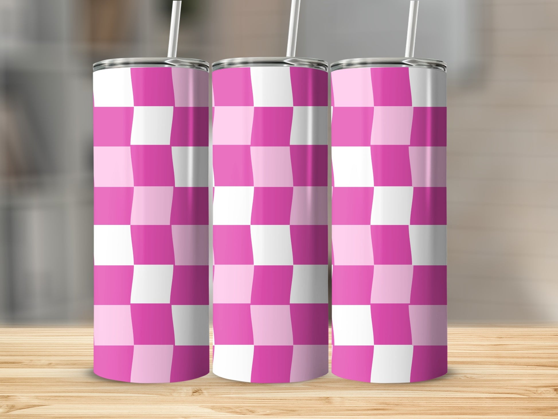 Three pink and white checkered tumblers with straws on a wooden surface.
