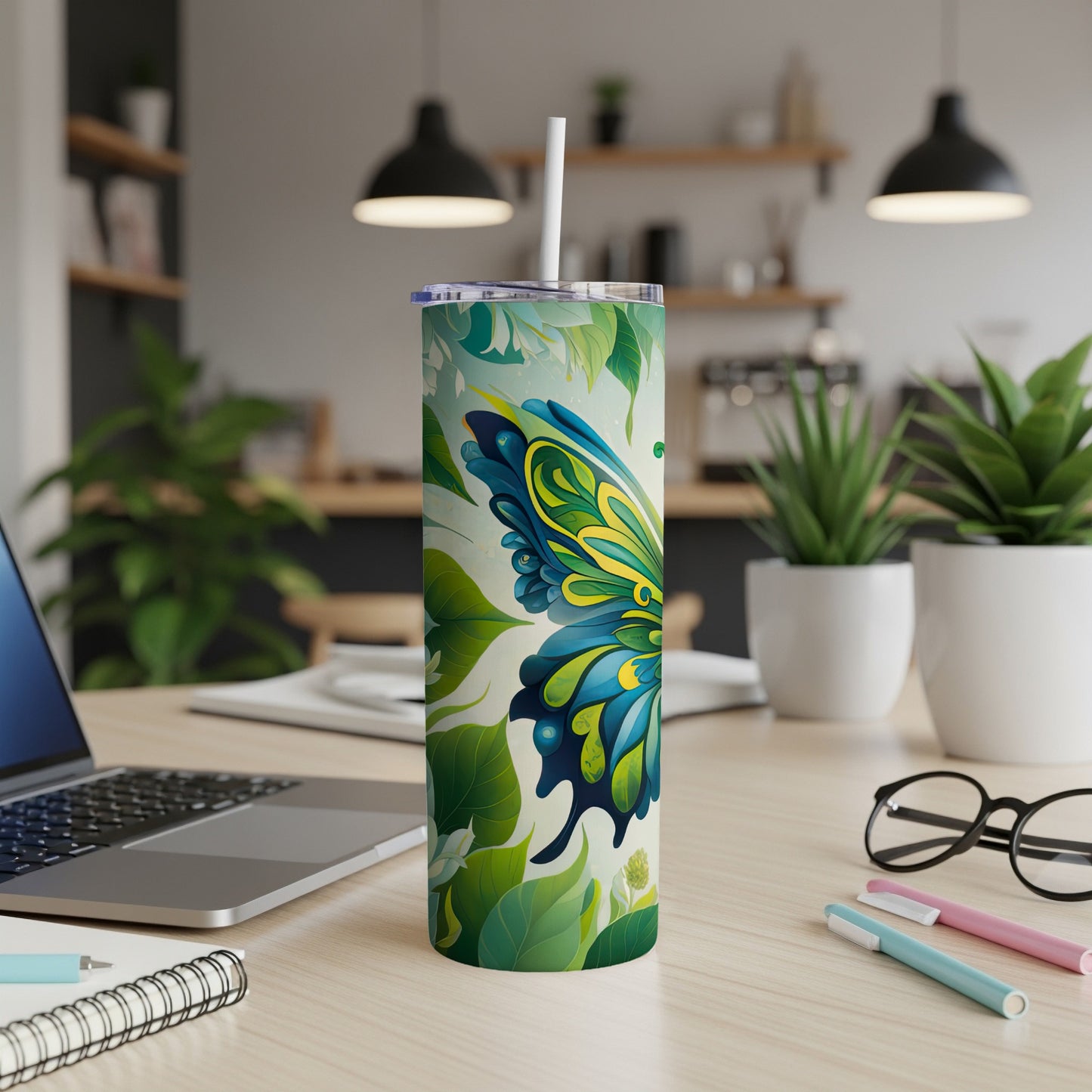 Green and blue butterfly tumbler with floral design on desk.