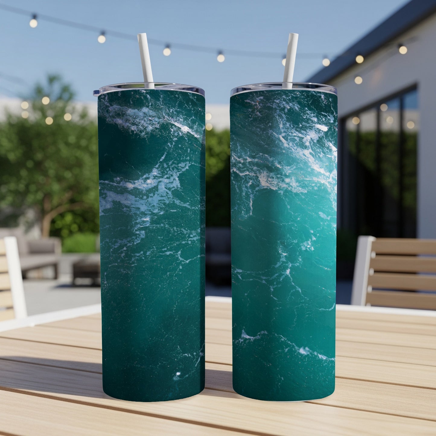 Two tall, teal tumblers with ocean wave pattern on outdoor table.