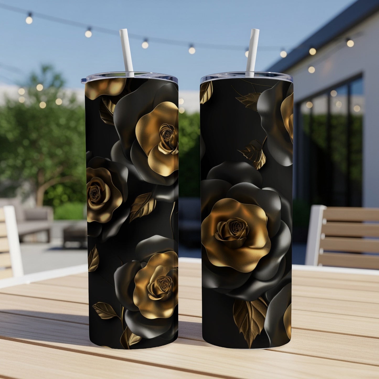 Two black tumblers with gold rose pattern and straws on a wooden table.