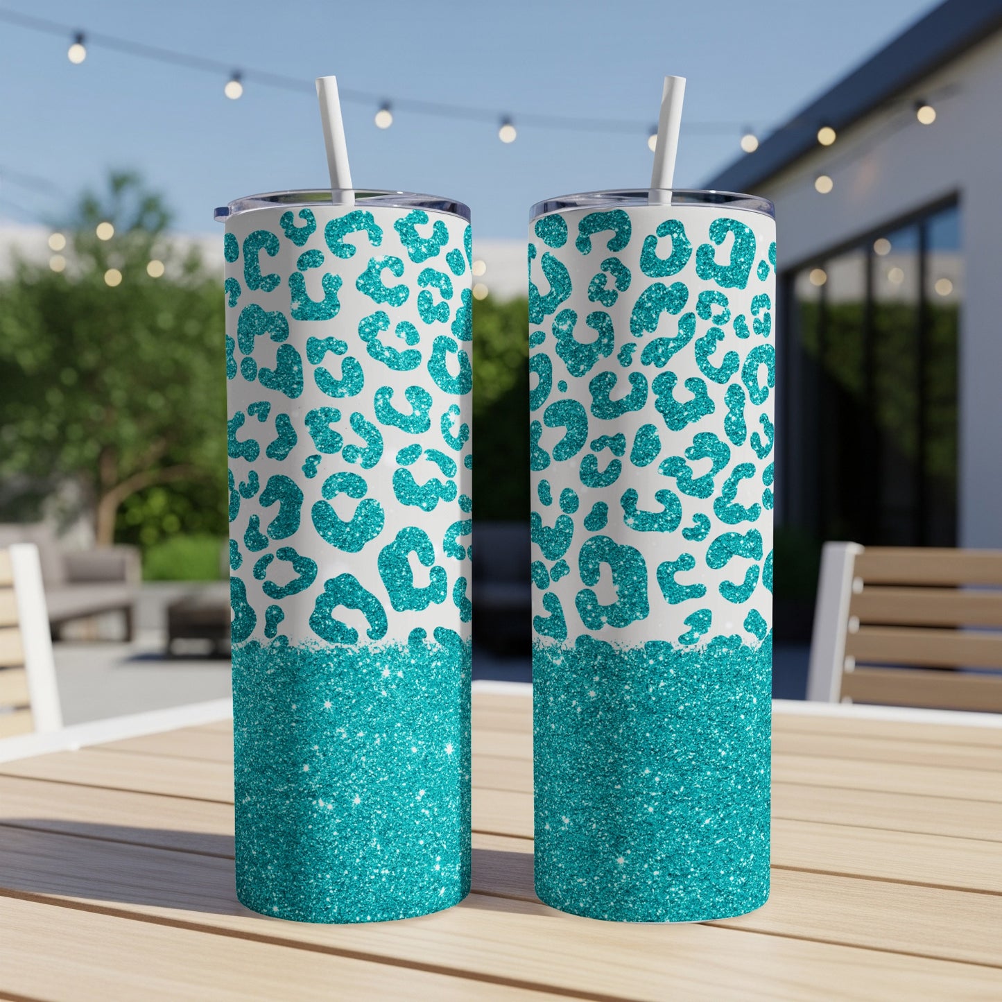 Two teal leopard print tumblers with glitter accents on a wooden table.