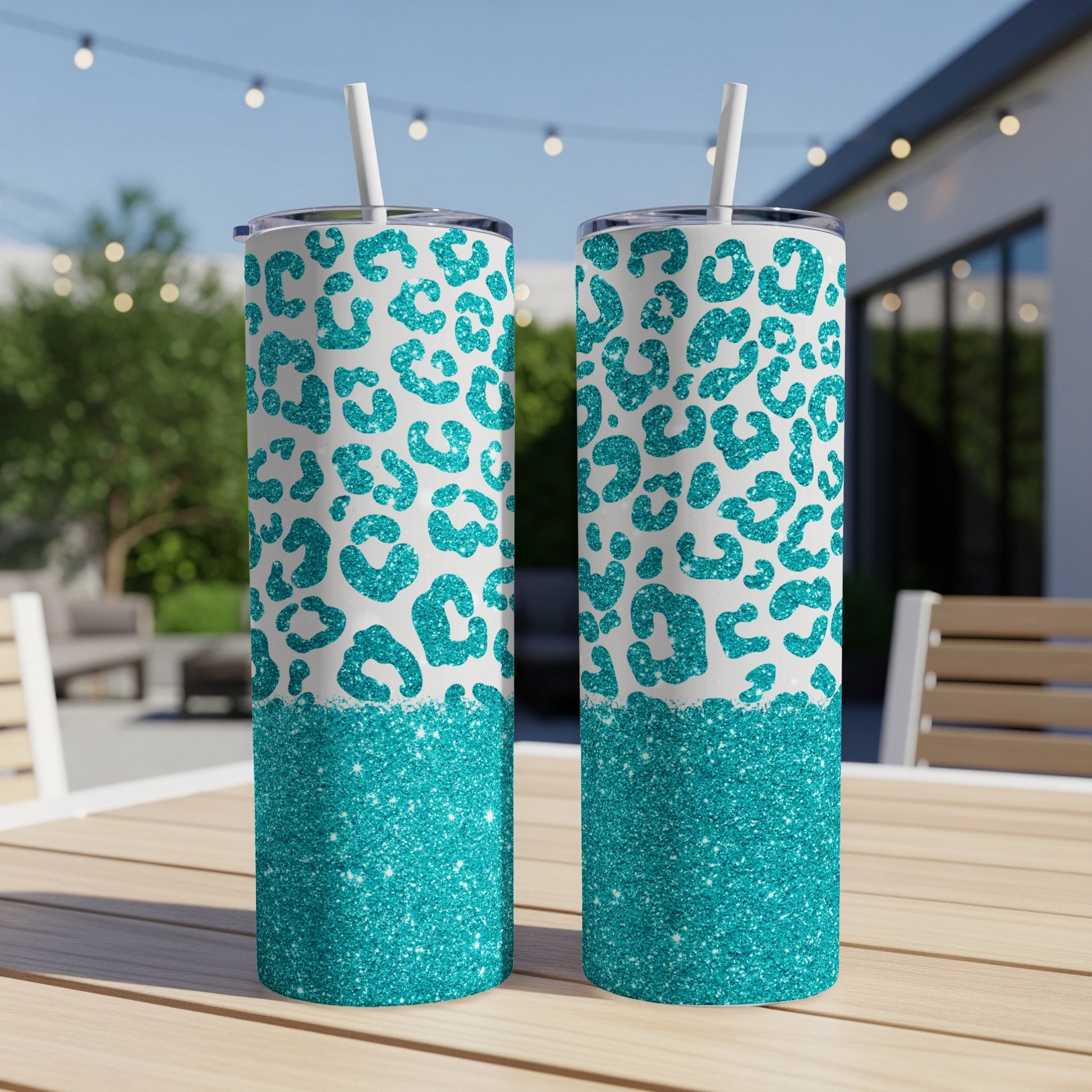 Two teal leopard print tumblers with glitter accents on a wooden table.