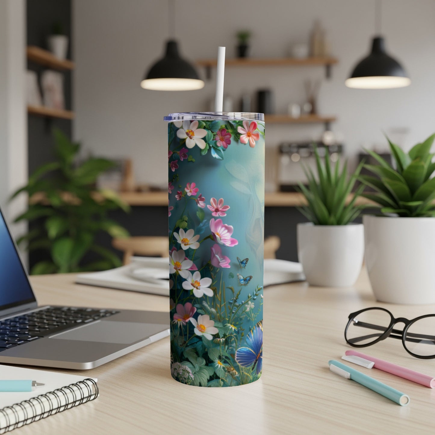 Floral tumbler with butterflies and a straw on a desk with a laptop.