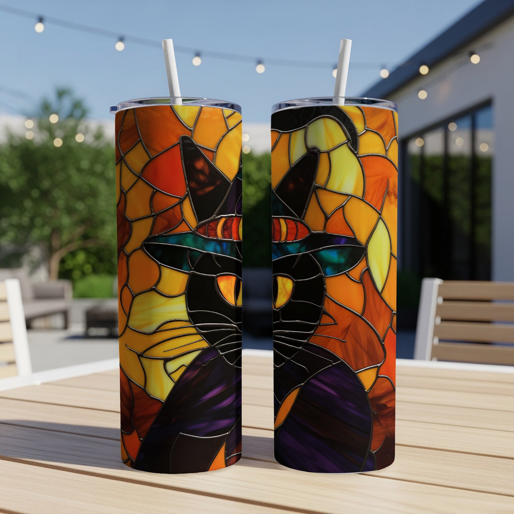 Black cat in witch hat, stained glass art, on two tumblers outdoors.
