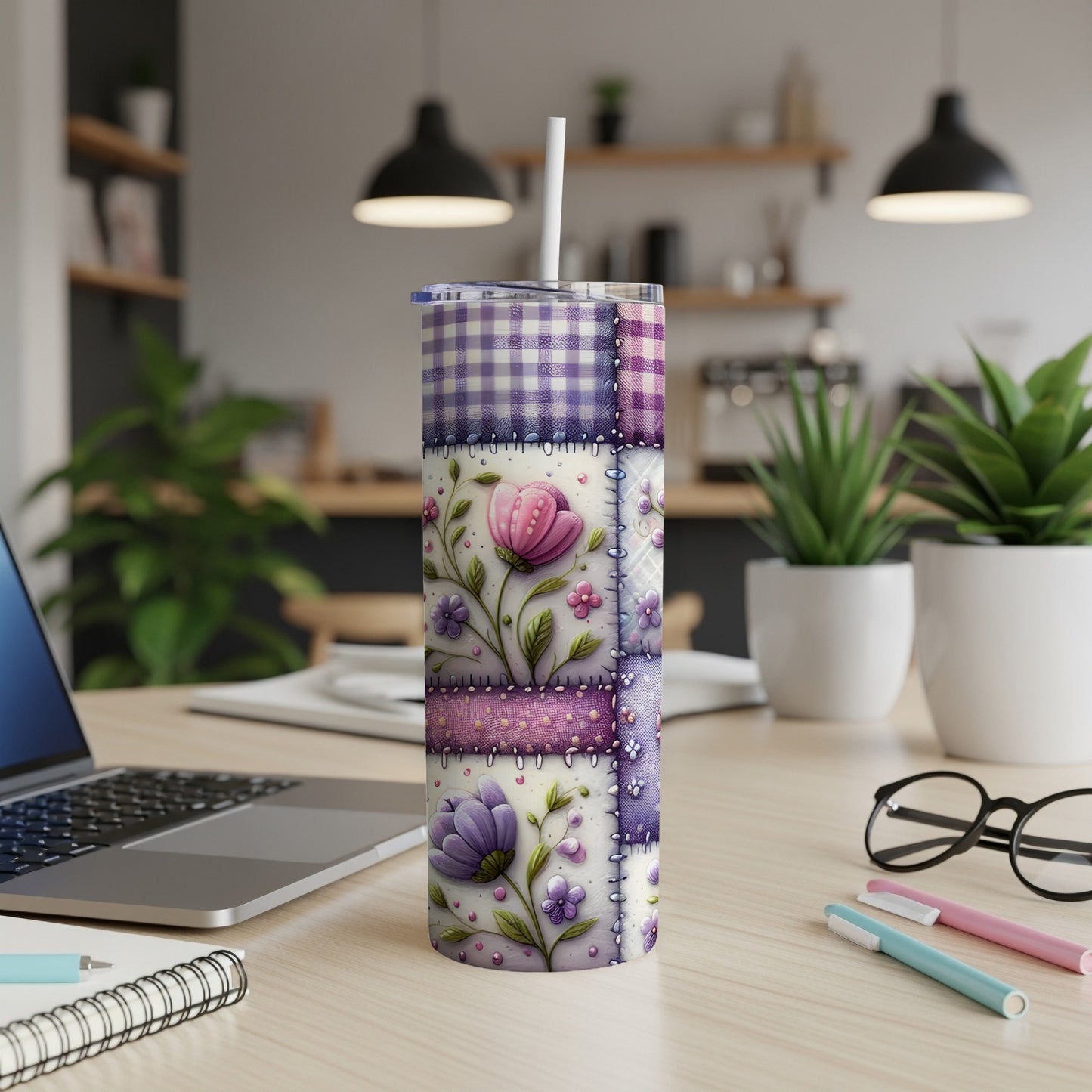 Purple and pink floral patchwork tumbler with a straw on a desk.