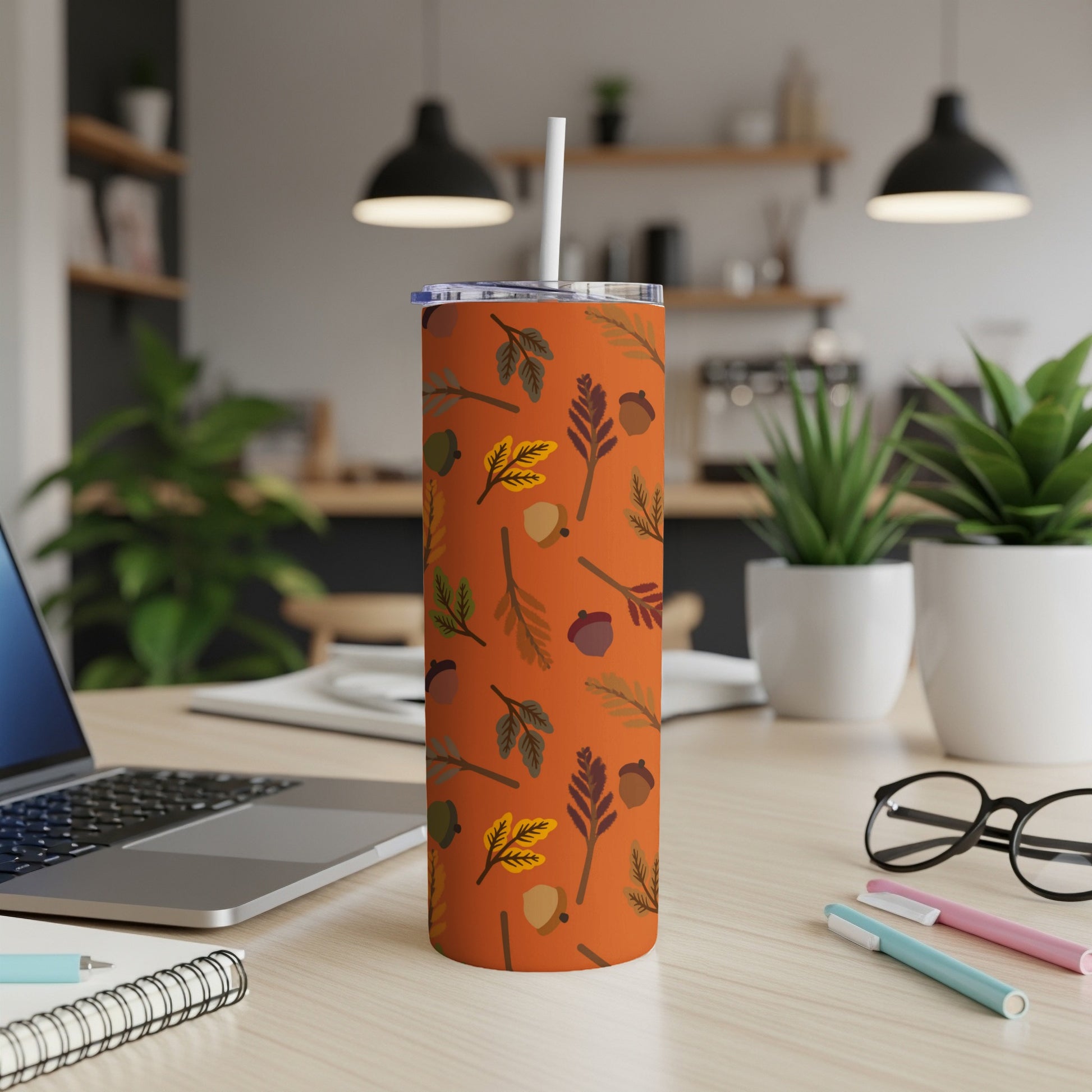 Orange tumbler with autumn leaf and acorn pattern.